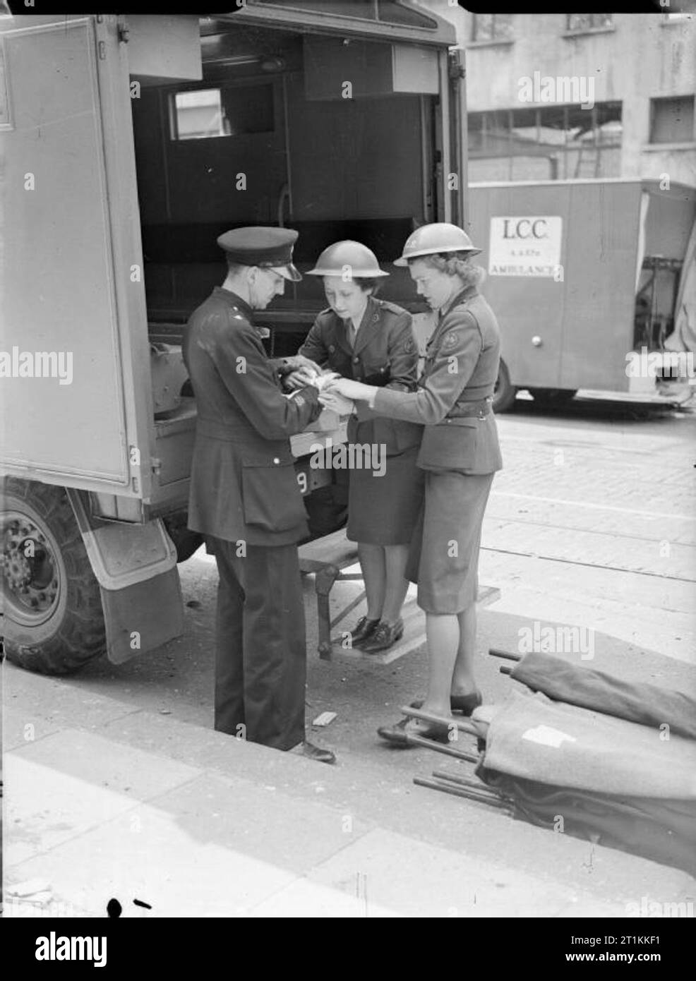 Flying Bomb- V1 Bomb Damage in London, England, UK, 1944 A police officer has his hand bandaged by women of the American Ambulance Great Britain following a V1 attack in Upper Norwood. The original caption states that the policeman's hand was injured by flying glass. Stock Photo