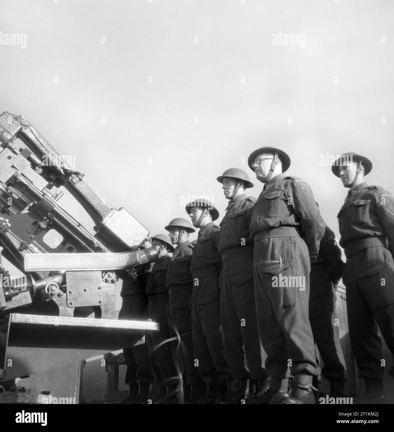 Home Guard Man Anti Aircraft Gun- Civil Defence in Britain, 1943 Members of the Home Guard line up for duty beside their anti-aircraft (AA) gun on a sunny Sunday morning. Stock Photo