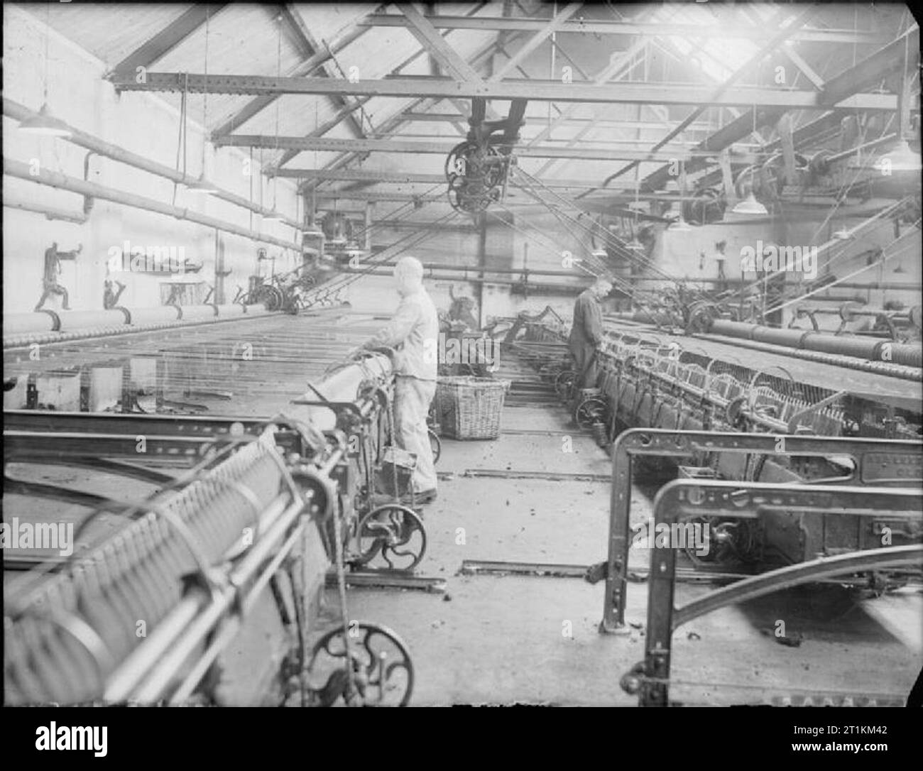 Huddersfield Cloth Mill- the work of C and J Hirst and Sons Ltd., Sunnybank, Longwood, Huddersfield, Yorkshire, England, UK, 1943 Mill workers man large yarn spinning machines at the mill of C and J Hirst and Sons Ltd. in Huddersfield. These machines spin wool into yarn, which will then be woven into cloth. Stock Photo
