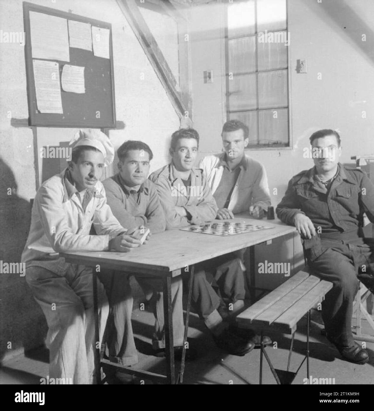 https://c8.alamy.com/comp/2T1KM9H/italian-prisoners-of-war-in-britain-everyday-life-at-an-italian-pow-camp-england-uk-1945-italian-prisoners-of-war-sit-at-a-table-at-an-outpost-of-the-n144-workers-camp-near-london-according-to-the-original-caption-the-outposts-allow-70-men-to-live-nearer-to-their-place-of-work-the-outposts-are-miniature-camps-with-refectories-dormitories-canteen-and-kitchen-as-in-the-bigger-camps-left-to-right-the-men-are-michele-spano-the-cook-e-ciardullo-a-tramontana-a-dalessandro-and-sergeant-marino-the-chief-of-the-outpost-a-game-of-draughts-is-set-up-on-the-table-2T1KM9H.jpg