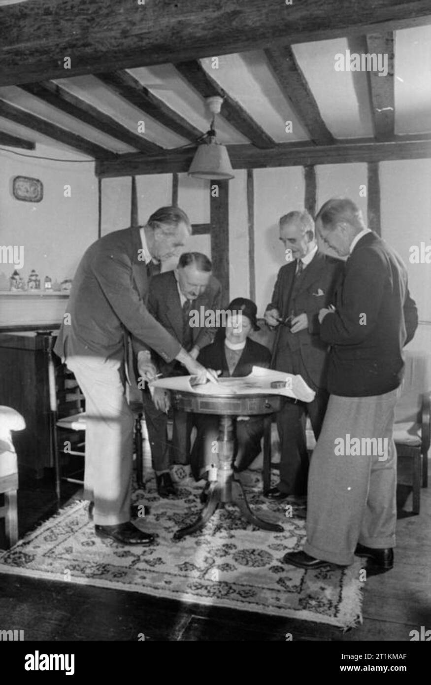 Invasion Village- Everyday Life in Orford, Suffolk, England, 1941 Members of the village Invasion Committee study the village's shelter system in the home of one of the committee members, 1941. Left to right they are: MP Walter Ross Taylor, County Councillor Arkle, Nurse Baker, Parish Council Chairman Chapman and Food Organiser Sir Henry Bunbury. Stock Photo