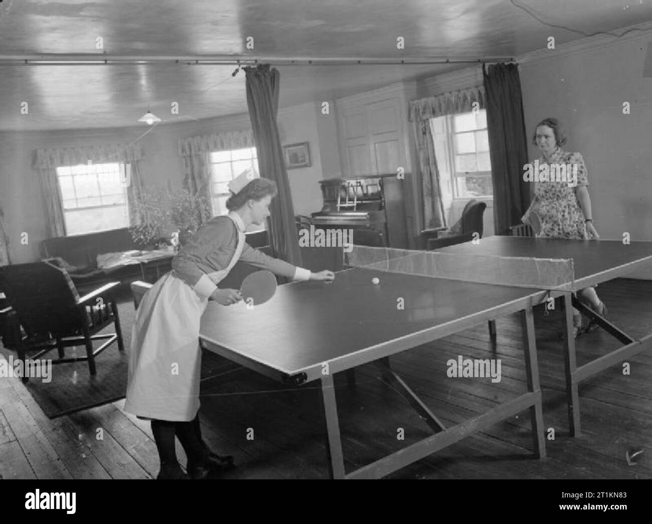 Mansion Becomes Maternity Home- Life at Brocket Hall, Welwyn, Hertfordshire, 1942 Two nurses (one in uniform, the other in civilian clothes) play table tennis or 'ping-pong' in their sitting room after a busy day at Brocket Hall maternity hospital. Stock Photo