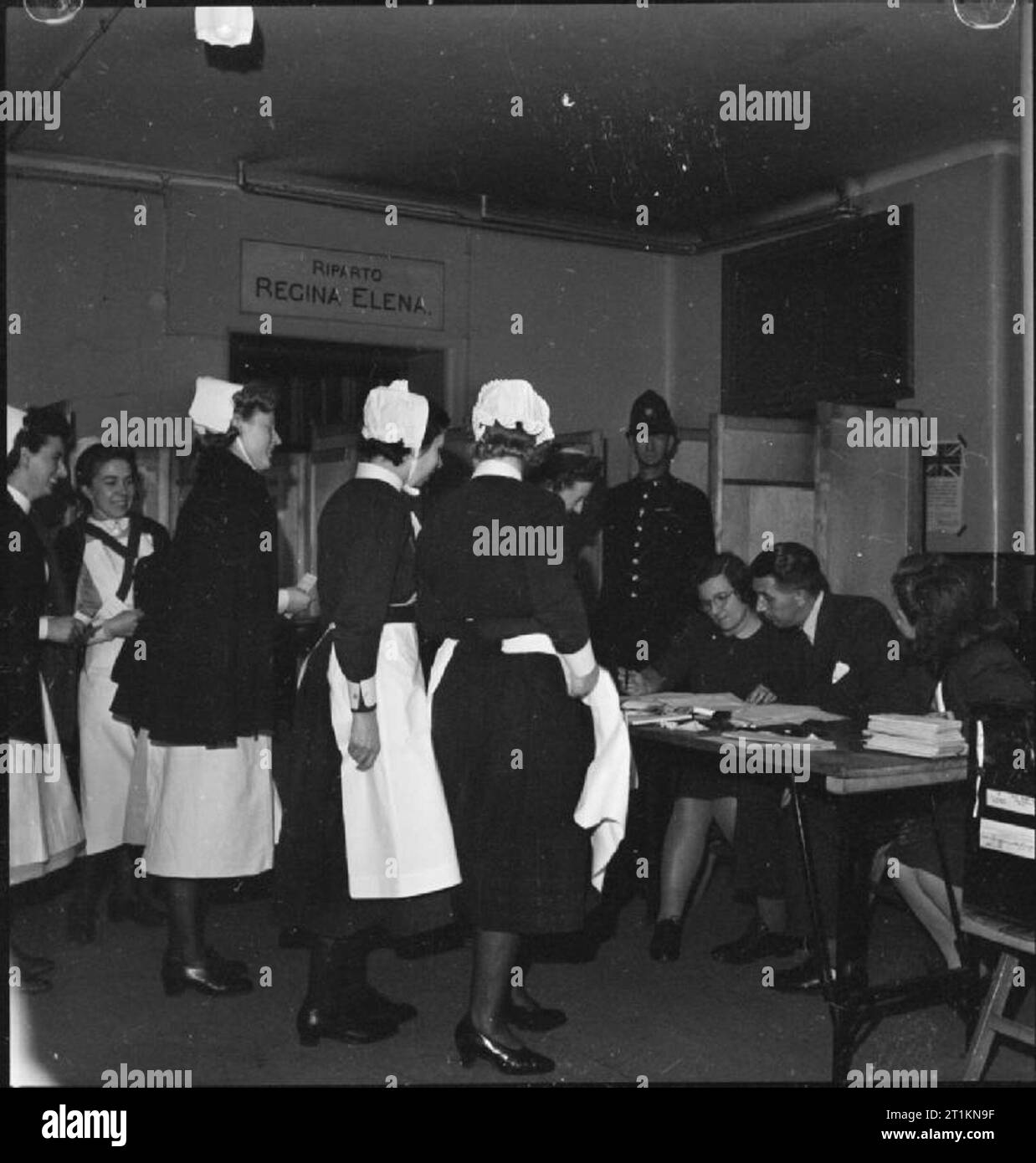 Londoners Record Their Vote on National Polling Day, Holborn, London, England, UK, 5 July 1945 A group of nurses from the nearby Great Ormond Street Hospital arrive at the polling station to cast their vote in the General Election. A policeman can be seen in the background, keeping an eye on proceedings, as the nurses are handed their ballot papers by officials. The pooling booths can be seen behind the policeman. This polling station is at the Italian Hospital, Queen Square, Holborn. Stock Photo