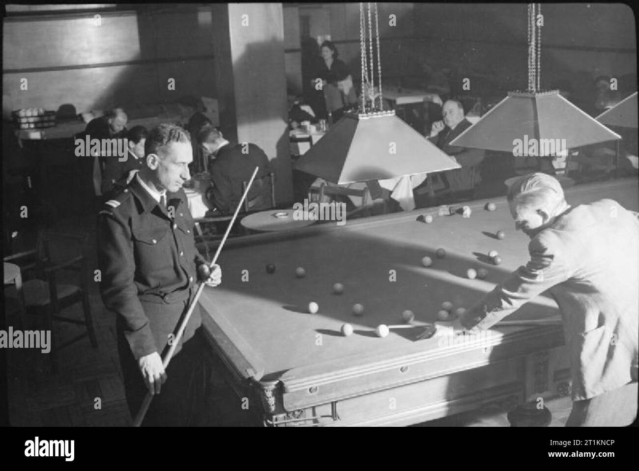 Merchant Navy Hotel- Naval Accommodation in Bedford Square, London, England, UK, 1944 Dr G C MacDiarmid (left) from Hamilton, New Zealand, and Mr C Lee (right), Fourth Engineer from Cape Town, South Africa, play a game of billiards in the dining room of the Merchant Navy Hotel in Bedford Square, London. The original caption states that Dr MacDiarmid 'has just been repatriated from Germany, where he was a prisoner of war for nearly four years'. Mr Lee served in the Royal Navy for two years before joining the Merchant Navy and was a survivor of a cruiser which was sunk at Crete. Stock Photo