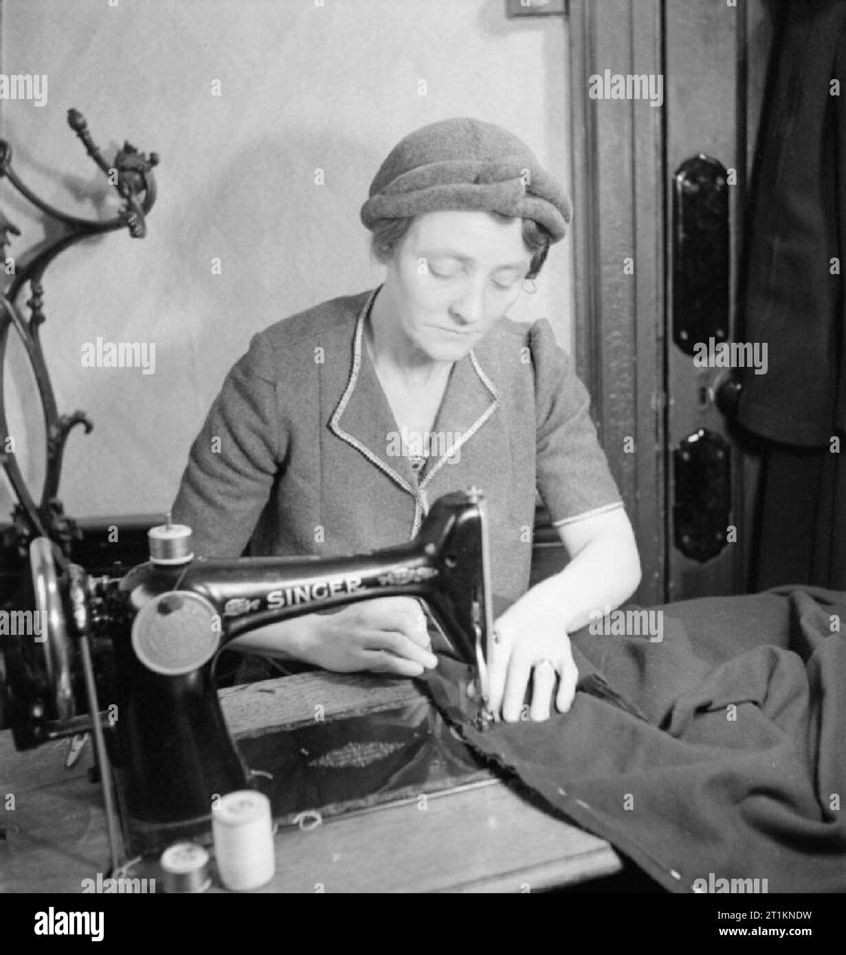 Mend and Make Do- Dressmaking Classes in London, 1943 Mrs Bolton at work on a sewing machine during a Make Do and Mend class in the office of the Kennington branch of the Labour Party. She is making a coat for her 16 year old daughter on the sewing machine that she has bought to the class as part of the 'Equipment Pool', to which all members of the class contribute. Stock Photo