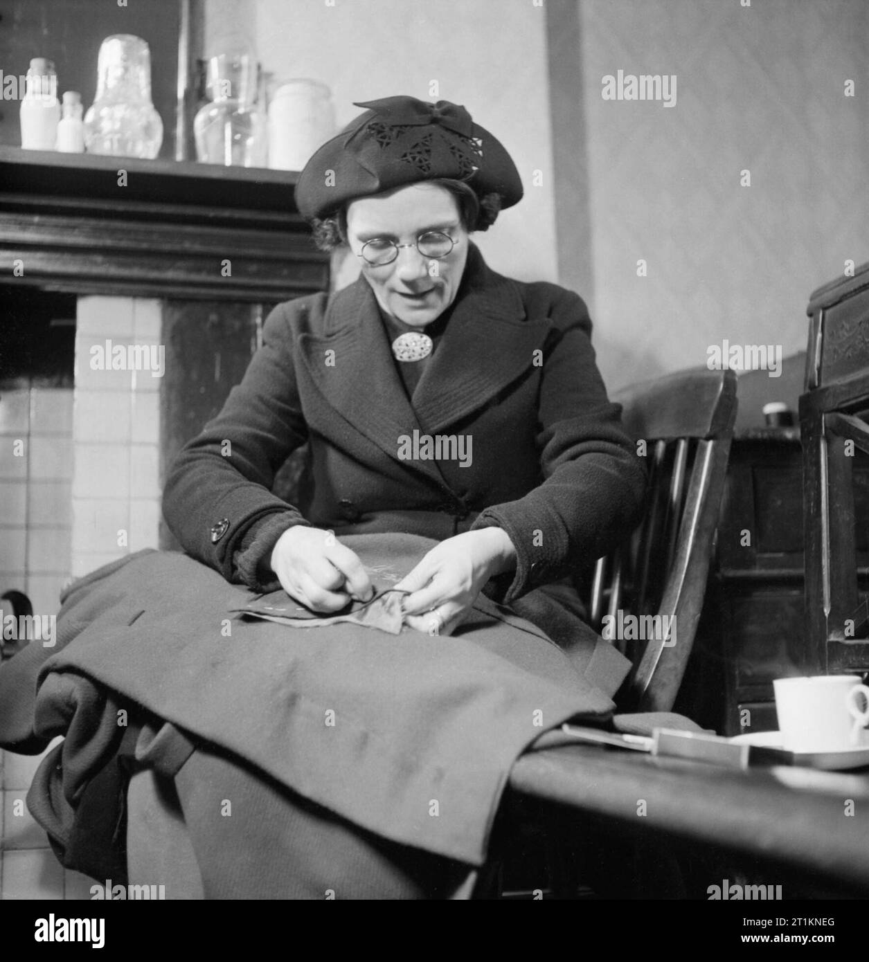 Mend and Make Do- Dressmaking Classes in London, 1943 Mrs K Holmes make a coat for one of her three children at the Make Do and Mend class she is attending. This class is held in the office of the Kennington branch of the Labour Party. She appears to be sewing a pocket on by hand. Stock Photo