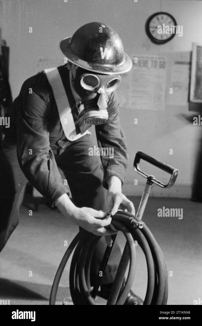 Air Raid Precautions on the British Home Front, C 1941 An Air Raid Warden wearing his steel helmet and duty gas mask checks that his stirrup pump is in order at his post, somewhere in Britain, c 1941. Stock Photo