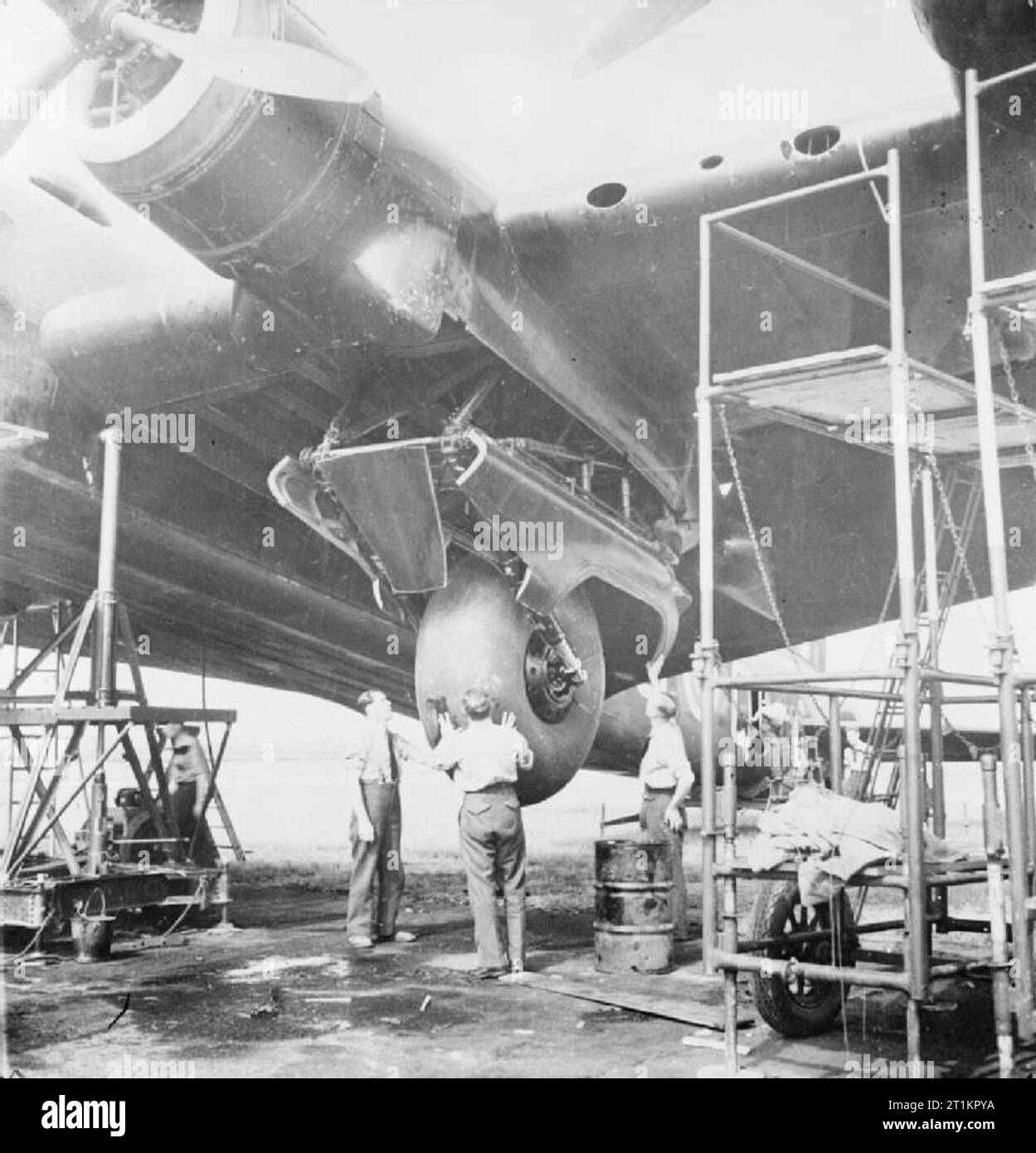 Royal Air Force Bomber Command 1939-1941. Mechanics checking the deployment of the main undercarriage of a Short Stirling of No. 7 Squadron RAF, supported on stands at Oakington, Cambridgeshire. Stock Photo