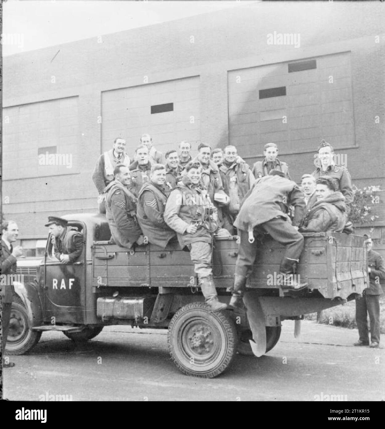 Royal Air Force Bomber Command 1939-1941. Bomber crews mount the flatbed of a dispersal truck before being transported to their aircraft for an operation. Most are wearing Irvin Harnessuits, a short-legged flying suit with an inbuilt life jacket and parachute harness, issued to Bomber and Coastal Command aircrew. Stock Photo