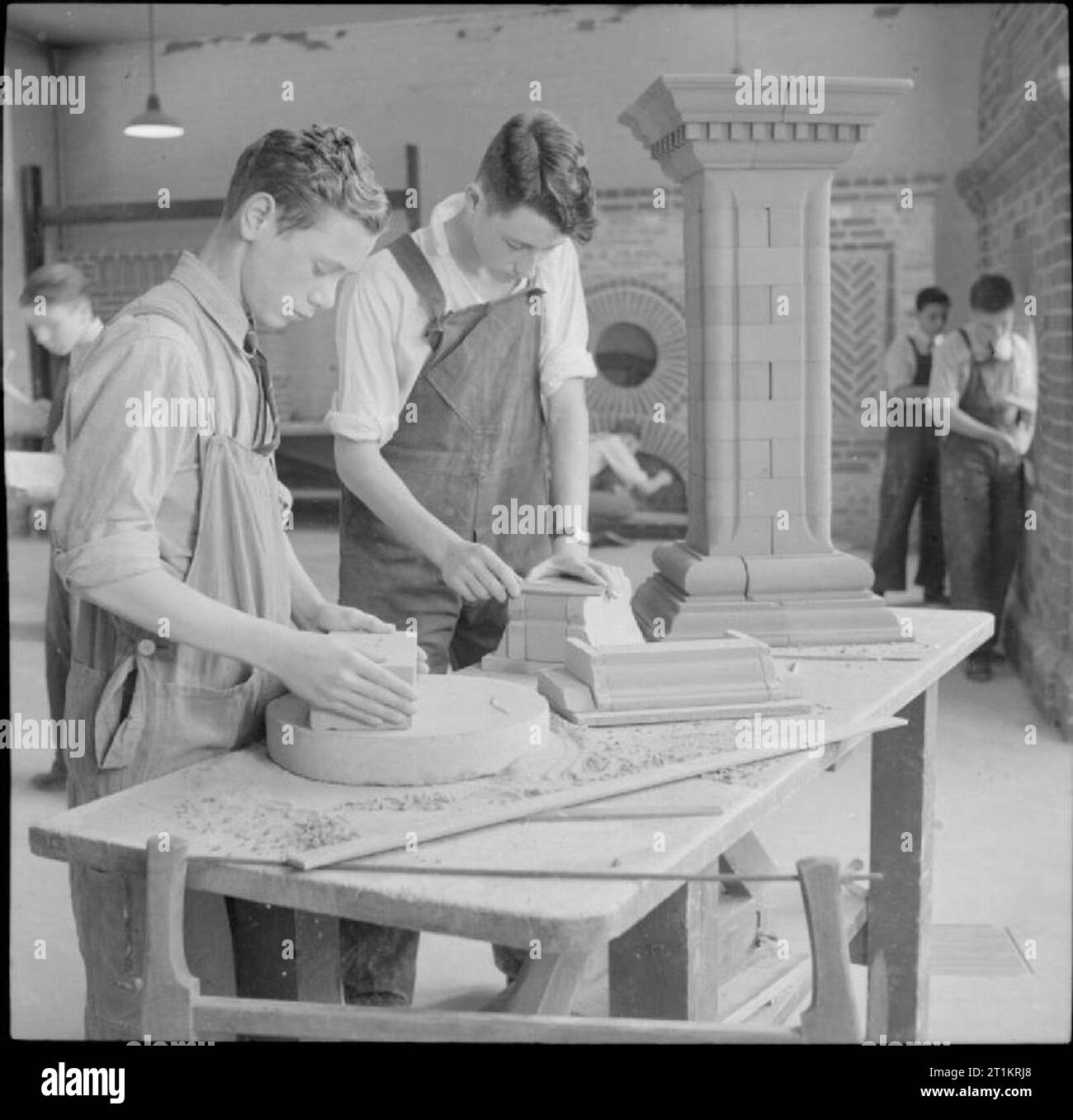 Technical School- Training at Tottenham Polytechnic, Middlesex, England, UK, 1944 Boys work on gauged brickwork during a lesson in the workshop at Tottenham Polytechnic. A large pillar which they have made can be seen on the table beside them. In the background, other boys are working on bricklaying, and their work, including a neatly pointed circular 'porthole' in a brick wall, is clearly visible. Stock Photo