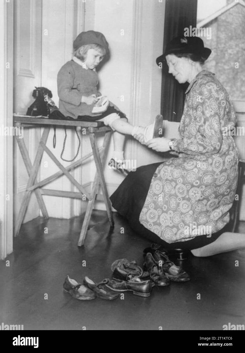 The work of the Citizens' Advice Bureau, Eldon House, Croydon, England, 1940 A young girl is fitted for new shoes by a female volunteer at the Citizens' Advice Bureau in Croydon. Stock Photo