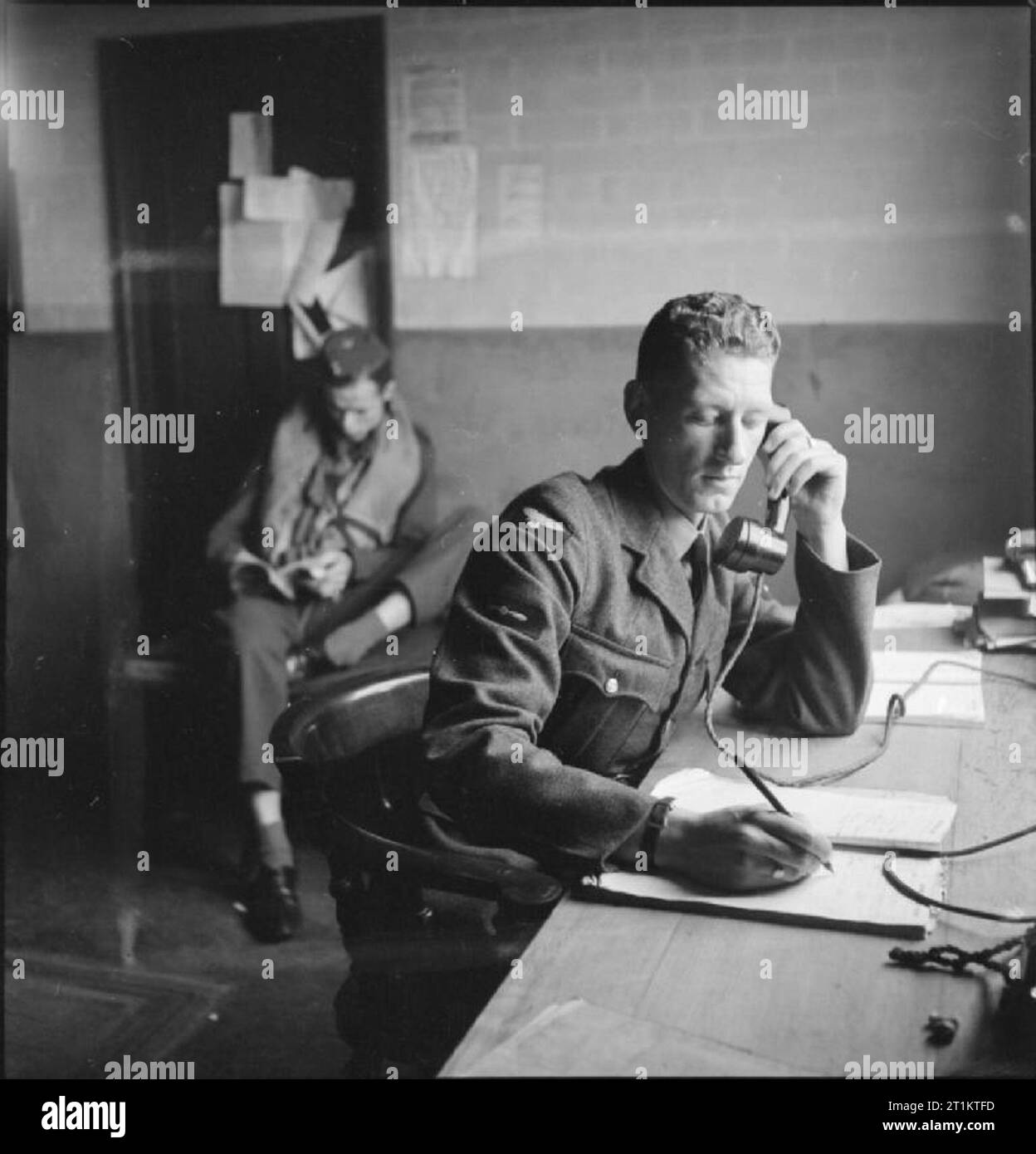 Americans in Britain- the work of No 121 (eagle) Squadron RAF, Rochford, Essex, August 1942 In the Dispersal Hut at Rochford airfield, the telephonist logs a call from the Control Tower, confirming that 12 Spitfires are successfully airborne. In the background, a 'spare' pilot reads a book. Stock Photo