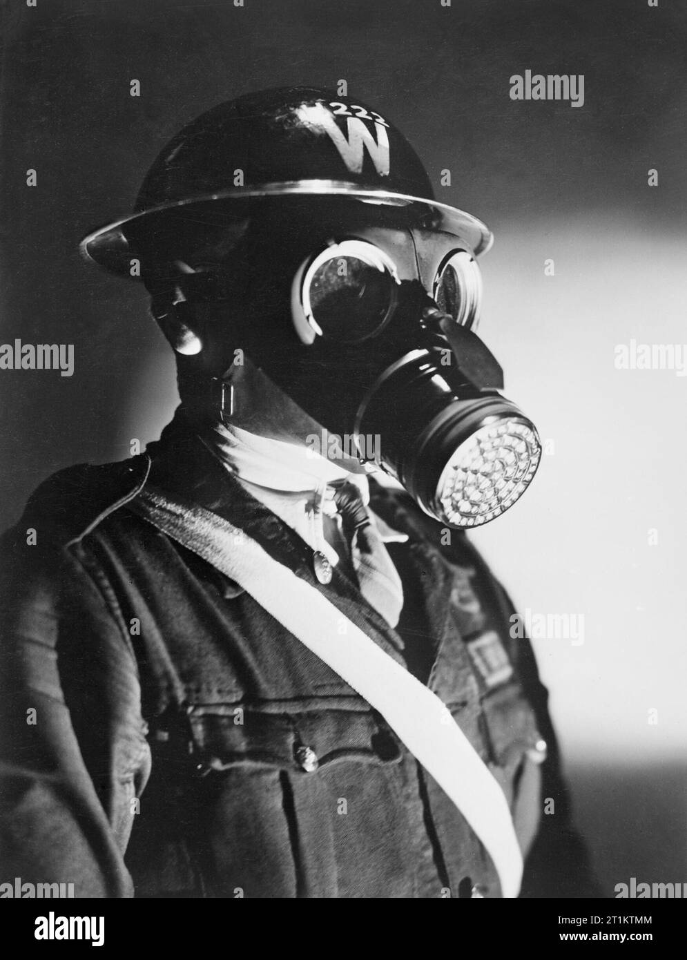 An Air Raid Warden wearing his steel helmet and duty gas mask during the Second World War. A head and shoulders portrait of an Air Raid Warden wearing his steel helmet and duty gas mask. The steel helmet has a large white 'W' painted on it, indicating that the wearer is an ARP Warden. The warden also wears a white sash, probably to make him more visible in the blackout. Stock Photo