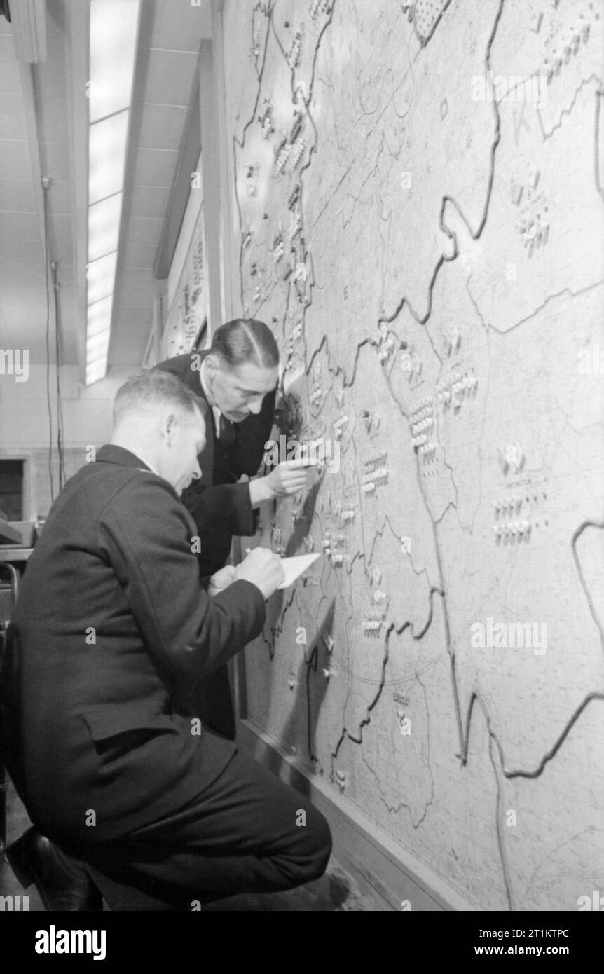 Two members of the Auxiliary Fire Service update an incident map nn the wall of the London Fire Brigade Headquarters, 1940. Two members of the Auxiliary Fire Service add pins, probably representing the current locations of fires or pumps, to a large map of London on the wall of the London Fire Brigade Headquarters. Stock Photo