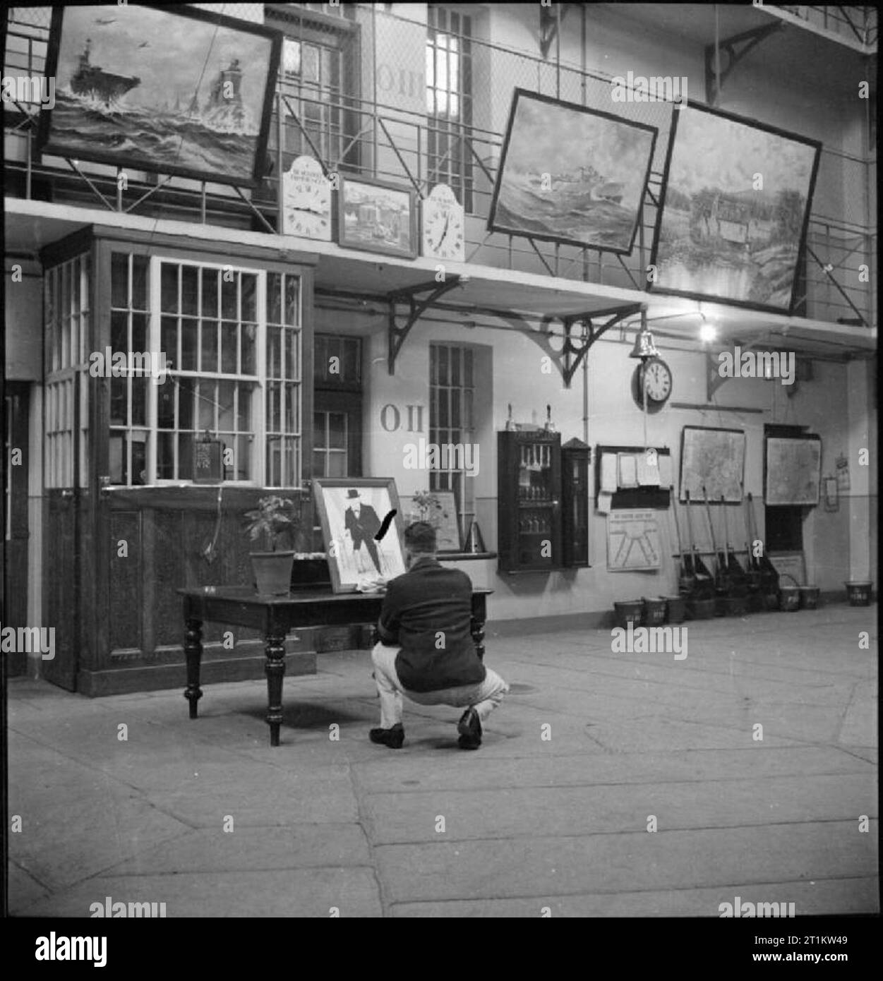 Wakefield Training Prison And Camp Everyday Life In A British Prison   Wakefield Training Prison And Camp Everyday Life In A British Prison Wakefield Yorkshire England 1944 An Inmate Crouches At A Table To Complete His Painting In The Central Hall Of Wakefield Training Prison The Hall Forms The Basis Of The Prison And Has Been Decorated With Paintings And Drawings Created By The Prisoners In Their Spare Time 2T1KW49 