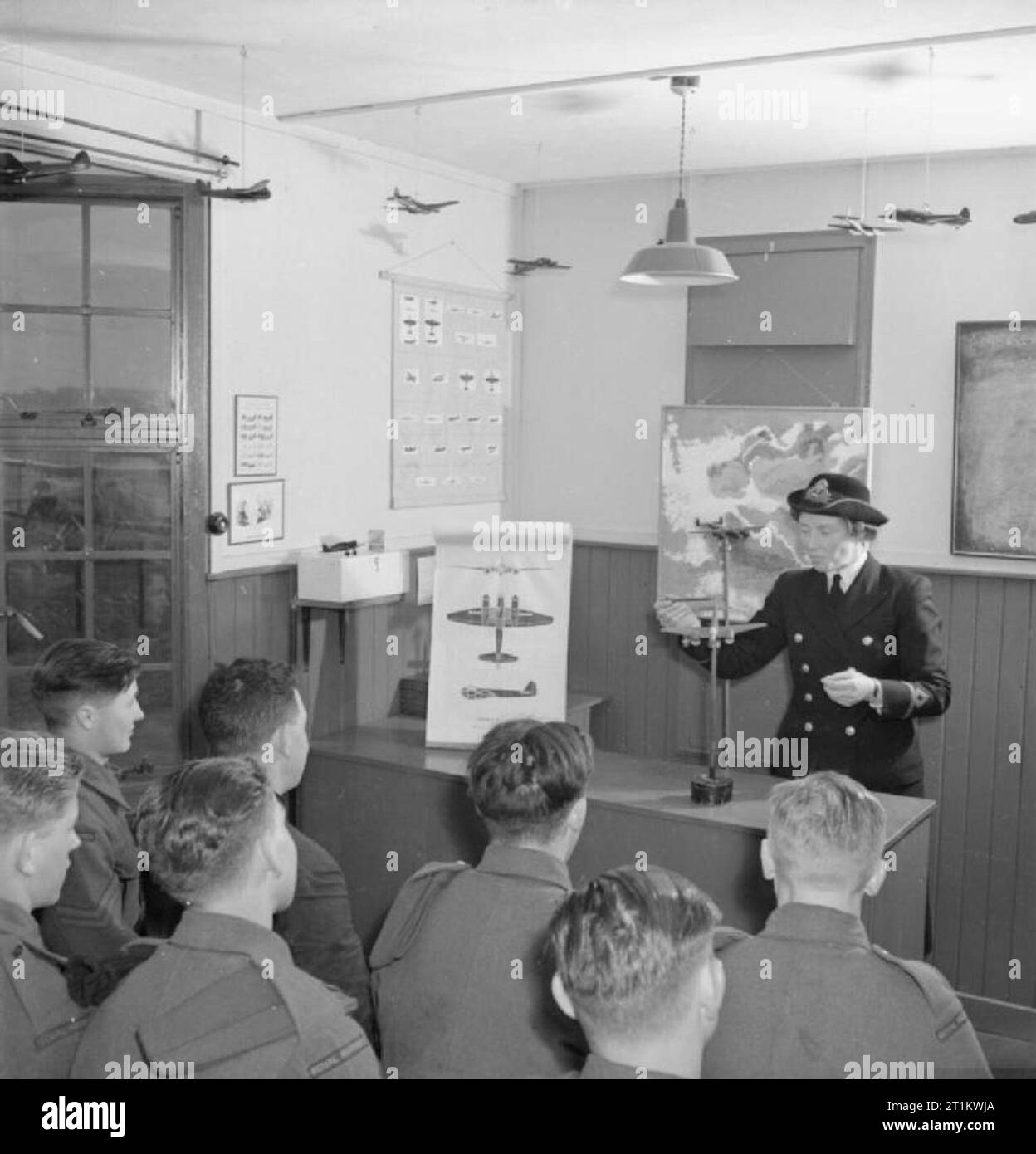 Women's Royal Naval Service- With the Fleet Air Arm, Scotland, 1943 Third Officer Ingledew, WRNS, gives a lecture on aircraft recognition to gunners of the Station Defence. She uses an epidiascope to project pictures of aircraft onto the screen as well as models of aircraft during her daily hour-long lecture. Stock Photo