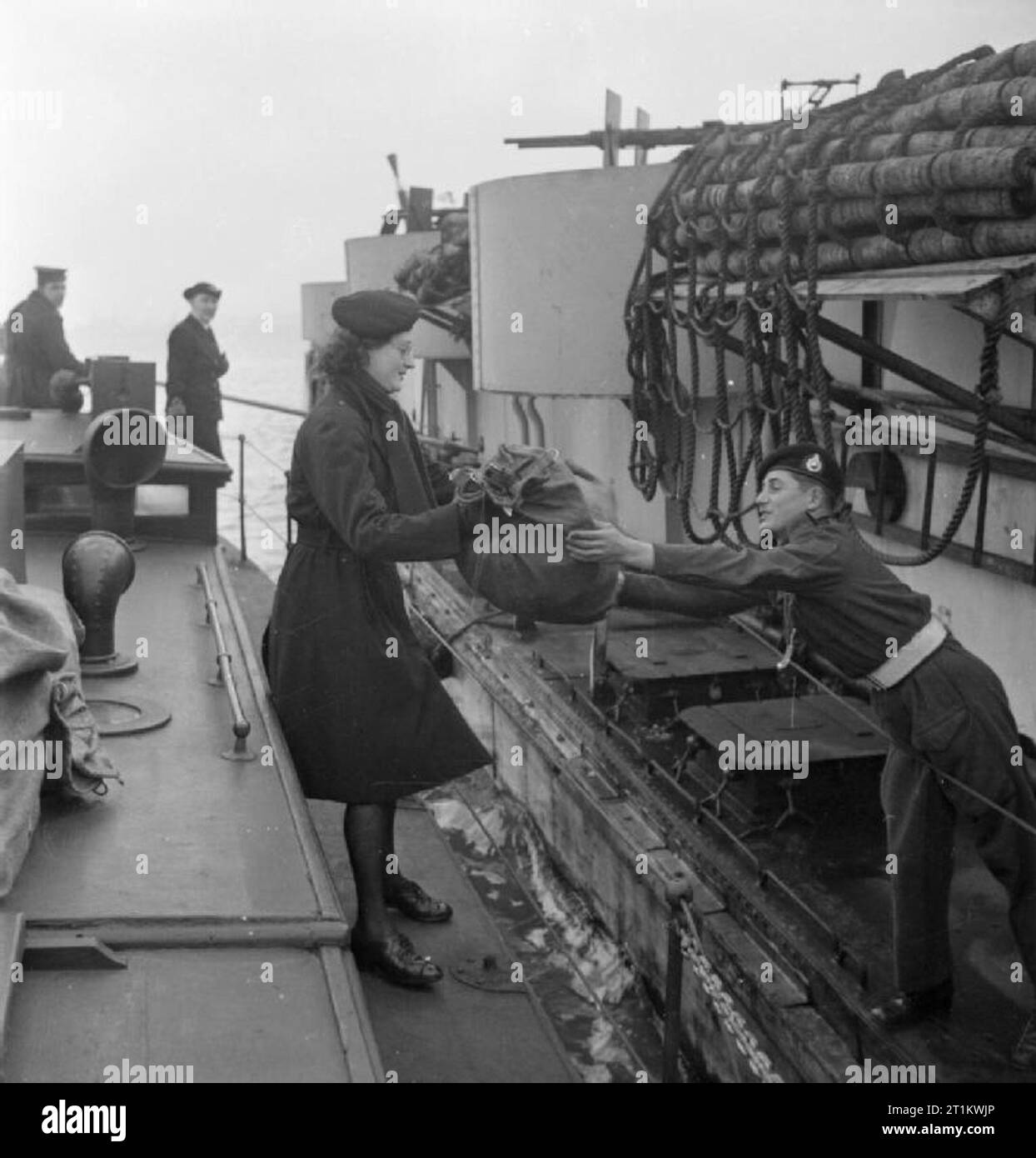 Women's Royal Naval Service- Wrens With the Fleet Mail, England, UK, November 1944 A Royal Marine stretches across from his landing craft to collect a sack of letters from a Wren of the Fleet Mail. The Wren is standing on the Mail Boat, which has come alongside the landing craft. Stock Photo