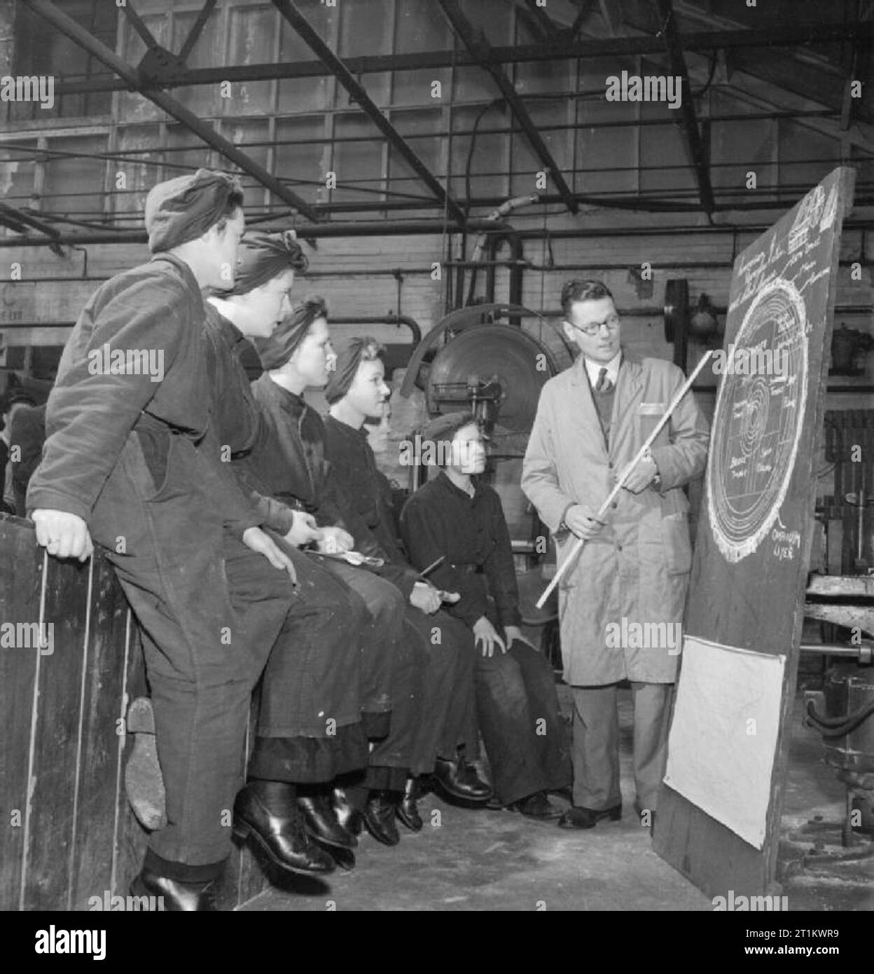 Wrens Train For New Job- Training For Ship Mechanics of the Women's Royal Naval Service, England, UK, 1943 A group of women of the WRNS listen to a lecture being given by their instructor on the conversion, shrinkage and defects of various types of timber, as part of their training to become Ship Mechanics (LC), probably at the Slough Government Training Centre. The diagram on the blackboard shows part of the trunk of a Douglas Fir tree, and explains how certain parts of the tree are most useful for certain types of job. Stock Photo