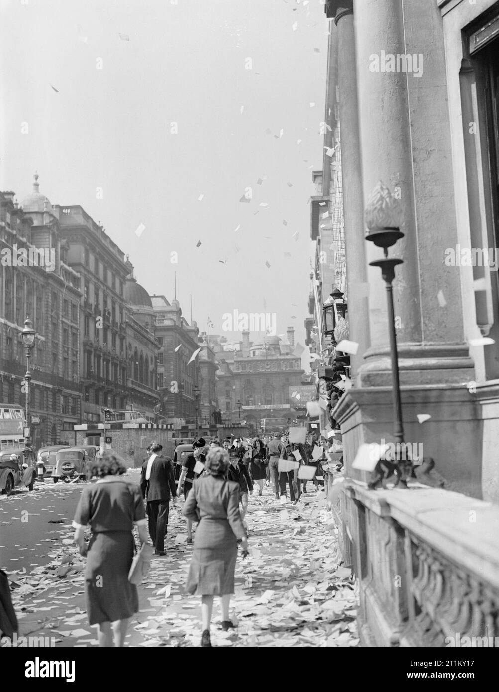 Britain Hears News of End of Jap War- Celebrating Victory in Japan, London, England, UK, c 15 August 1945 Civilians walk amongst the piles of torn up paper which have been thrown, 'ticker tape'-style, from the windows of offices, on Lower Regent Street, London, to celebrate the signing of the Peace with Japan. More paper can be seen fluttering down onto the pavement and road: many vehicles appear to have stopped. It appears that this photograph was taken on Lower Regent Street, looking back up towards Piccadilly Circus. In the middle of the road (left of the photograph), a brick surface shelte Stock Photo