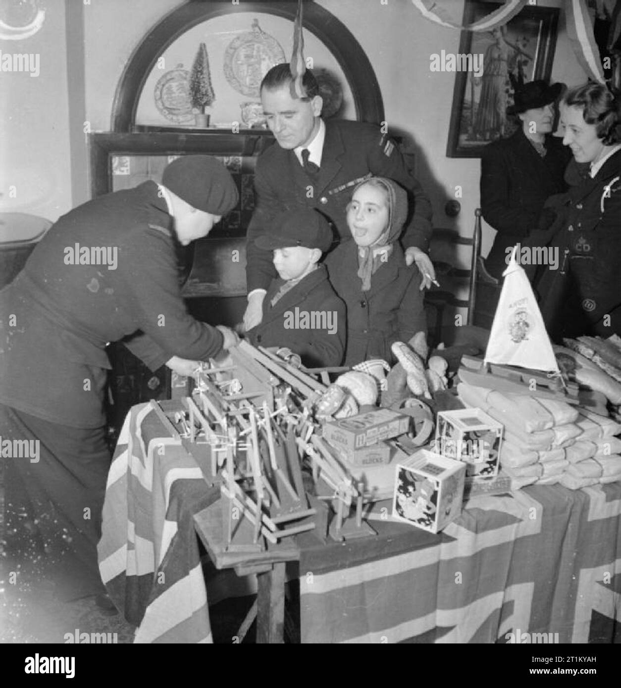 Bwrs Christmas Gifts Distributed To London's East Enders- American Aid To the Canning Town Settlement, London, England, UK, December 1944 Two young children at Canning Town settlement choose a toy each from the selection of gifts donated by America. They are assisted by two members of Civil Defence (possibly their parents). According to the original caption, there were 700 children at the settlement. Stock Photo