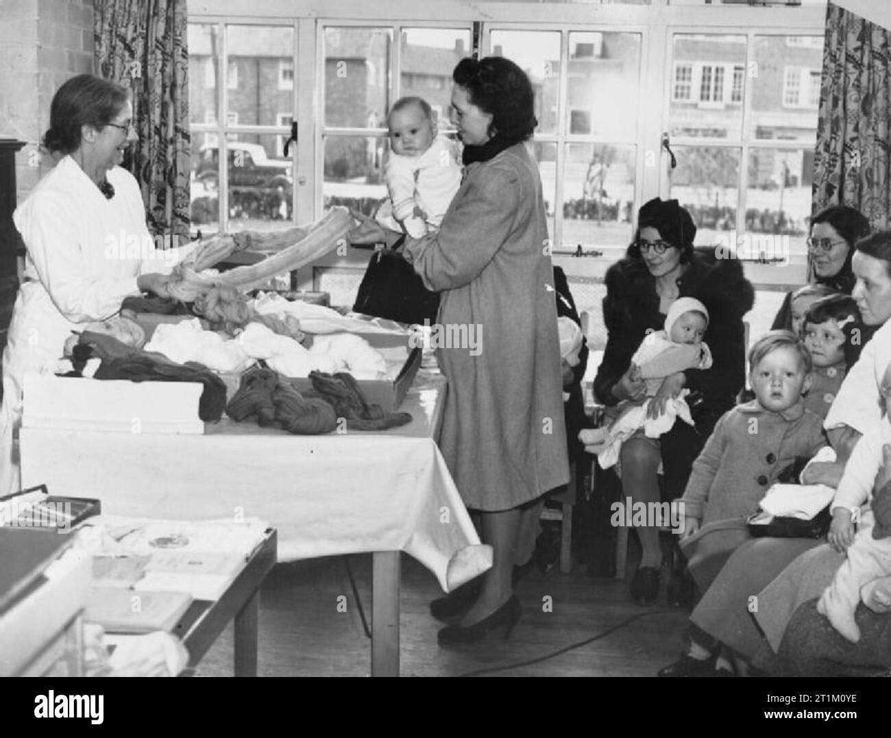 The Civilian Evacuation Scheme in Britain during the Second World War The Welfare and Social Centres in England's villages are doing magnificent work, not only for their own people but for the hundreds of thousands of evacuees who are now living amongst them. Photo shows: Women and children collect wool for children's clothing from a centre in a Hertfordshire village. Stock Photo