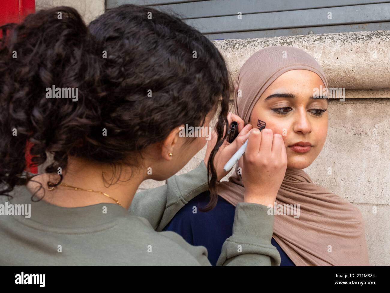 London, UK. 14 Oct 2023: A pro-Palestinian woman has a Palestinian flag drawn on her cheek in Whitehall, London,  at a protest in support of Palestine and against  Israeli attacks on Gaza. Stock Photo