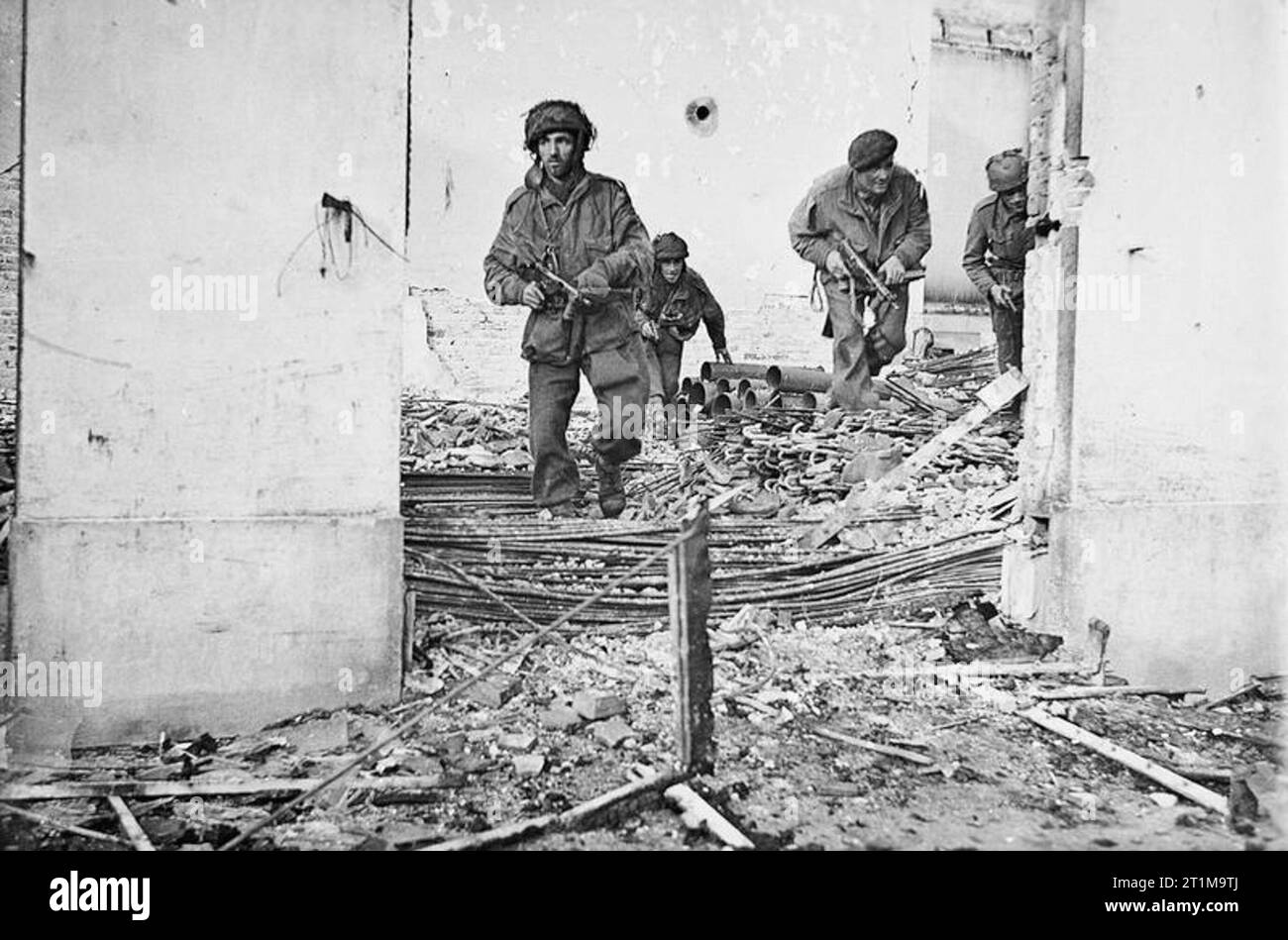 British airborne troops moving through a shell-damaged house in ...