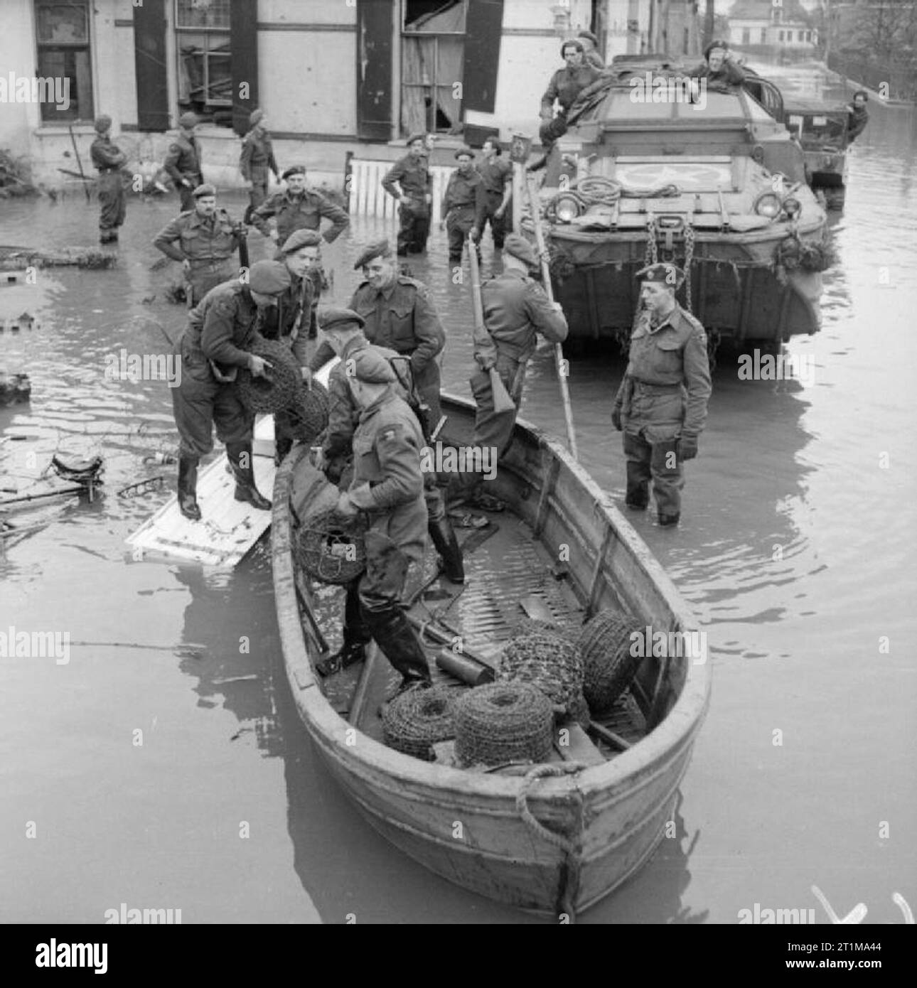 The British Army in North-west Europe 1944-45 Troops from the York and Lancaster Regiment unloading coils of barbed wire from a boat in the flooded village of Zetten, 2 March 1945. Stock Photo