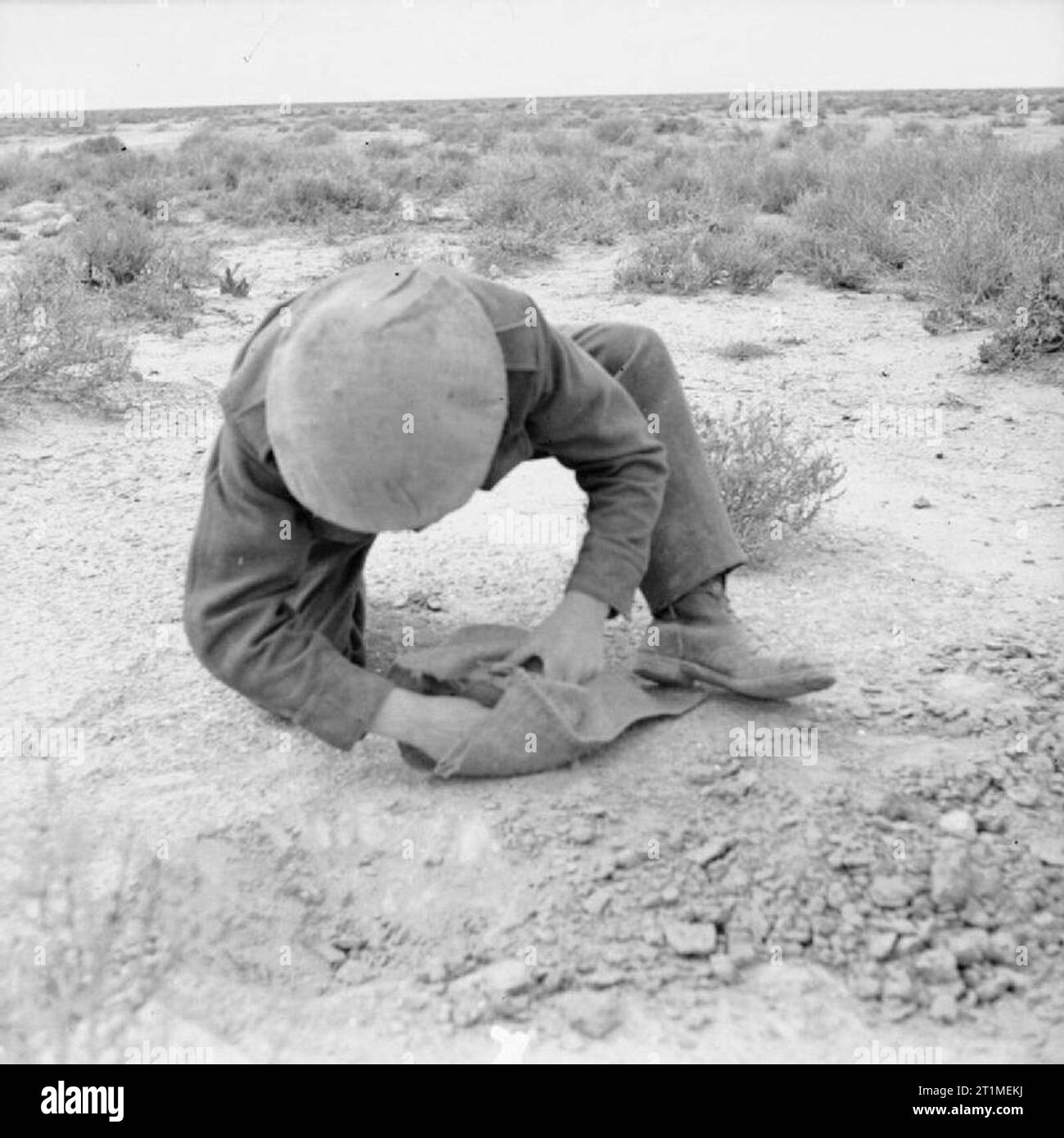 The Campaign in North Africa 1940-1943 A British soldier laying a mine in the sand, 6 April 1942. The mine is placed in a sack and buried with its top level with the ground. 5lb of pressure is required to set it off. Stock Photo