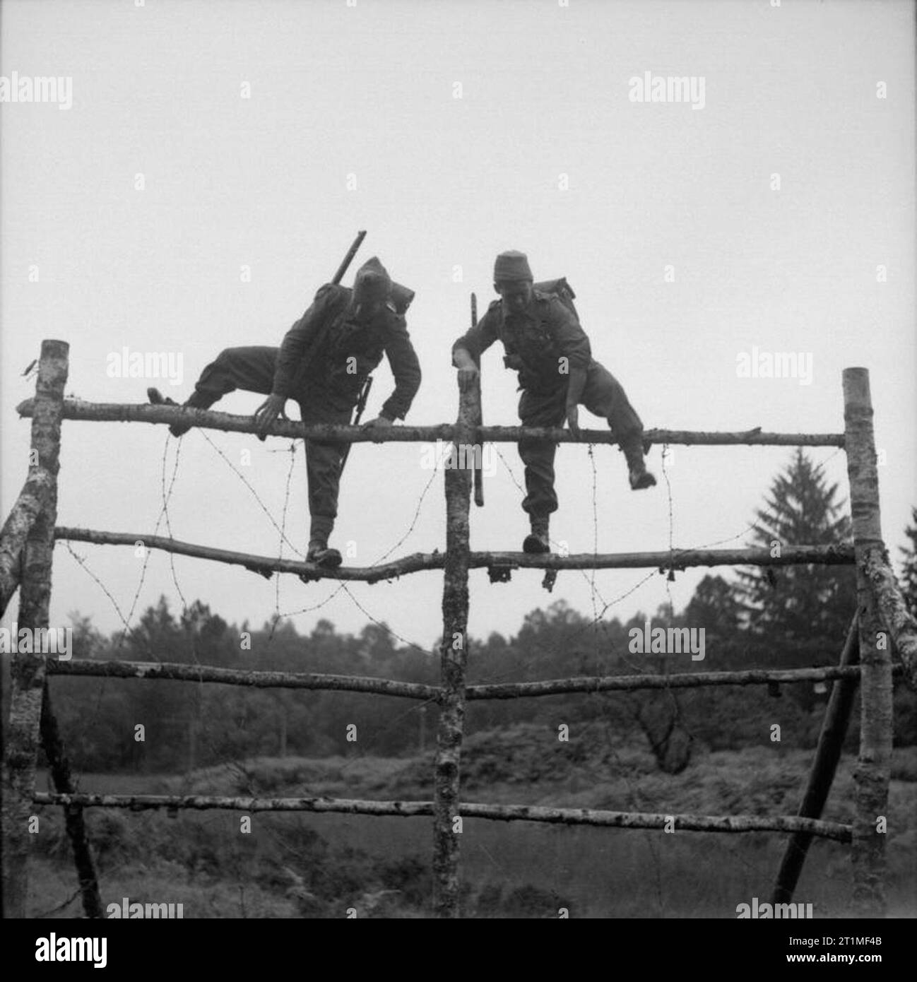 The Free French Army in the United Kingdom 1939-1945 French commando troops undergoing training at Achnacarry House in Scotland: Free French troops climbing over a high obstacle from which they have to jump onto boggy ground on the assault course. Stock Photo