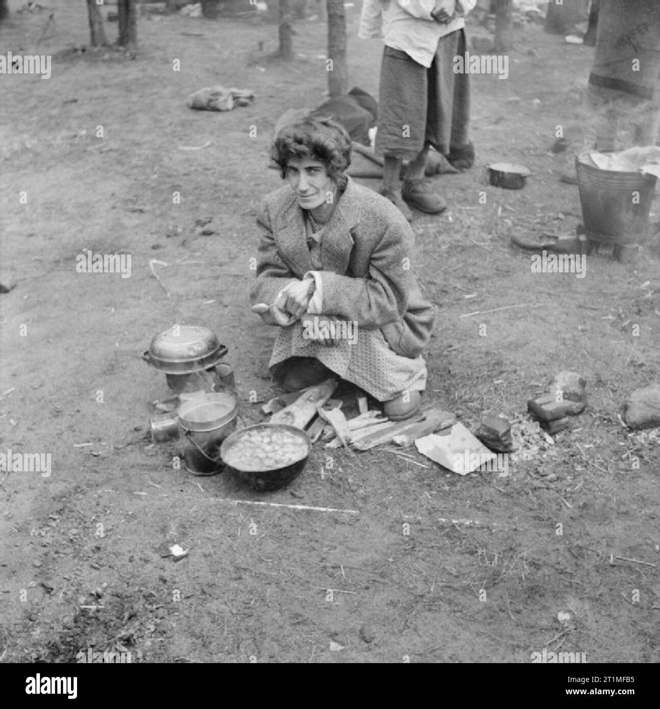 The Liberation of Bergen-belsen Concentration Camp, April 1945 An emaciated woman inmate cooks a meal in the open air. Stock Photo
