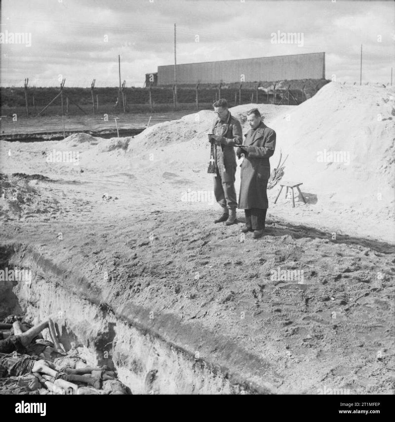 The Liberation of Bergen-belsen Concentration Camp, April 1945 Two British Army chaplains, Rev Leslie H Hardman, Senior Jewish Chaplain to the 2nd Army, and the Roman Catholic Padre Father M C Morrison, conduct a service over one of the mass graves before it is filled in. Stock Photo