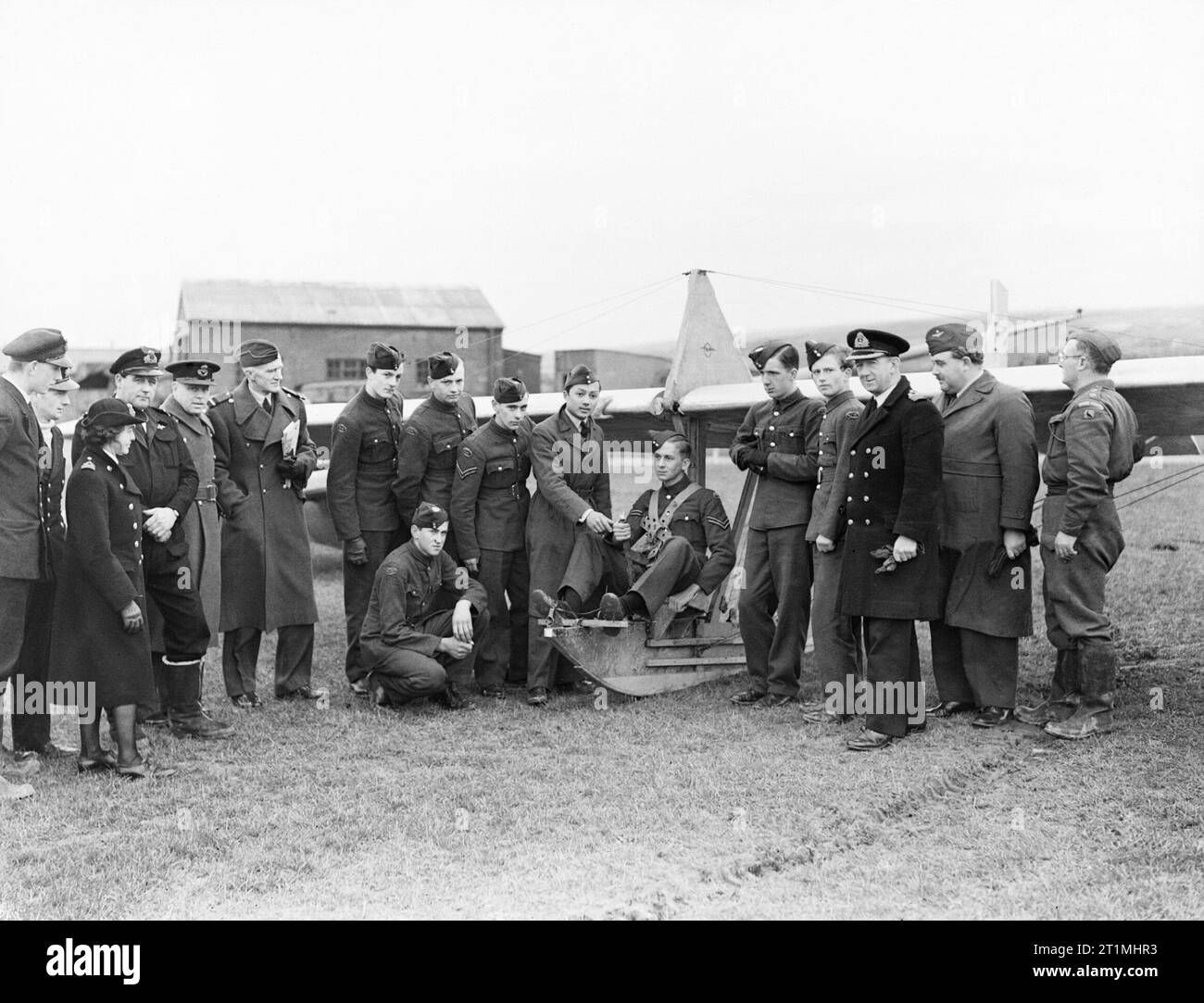 Air cadets learn the basics of flight at RNAS St Merryn in Cornwall, February 1944. Flight Lieutenant Prince Birabangse, well known in peacetime as the racing motorist B Bira, but now Chief instructor at the school, shows a cadet how to handle the controls of an elementary glider. From left to right: Sub Lieut (A) W A Murray, RNVR, an instructor; Lieut Cdr (A) K Garston-Jones, RNVR, Chief Liaison Officer to the ATC for HMS VULTURE; Squadron Leader Sir John Mclesworth St Aubyn; Air Commodore W Sawrey; Flight Lieut Prince Biribangse, Capt W P McCarthy, RN, Commanding Officer HMS VULTURE; Flying Stock Photo