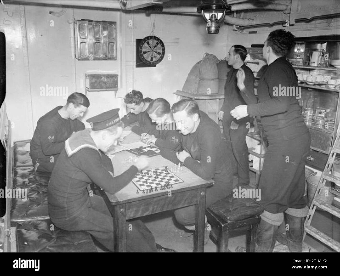 The Polish Navy during the Second World War The Foreigners' Mess on board the Polish Navy destroyer ORP Piorun. The seven British ratings in the mess they have to themselves, left to right: coder (who kept a boarding house in civilian life), signalman (Bank of England clerk), signalman (timber merchant), and telegraphist and signalman (regulars). Playing darts are the anti-U-boat worker and HO signalman, while the other men are playing chess or writing letters. The anti-sub man was awarded the DSM for his work. Stock Photo