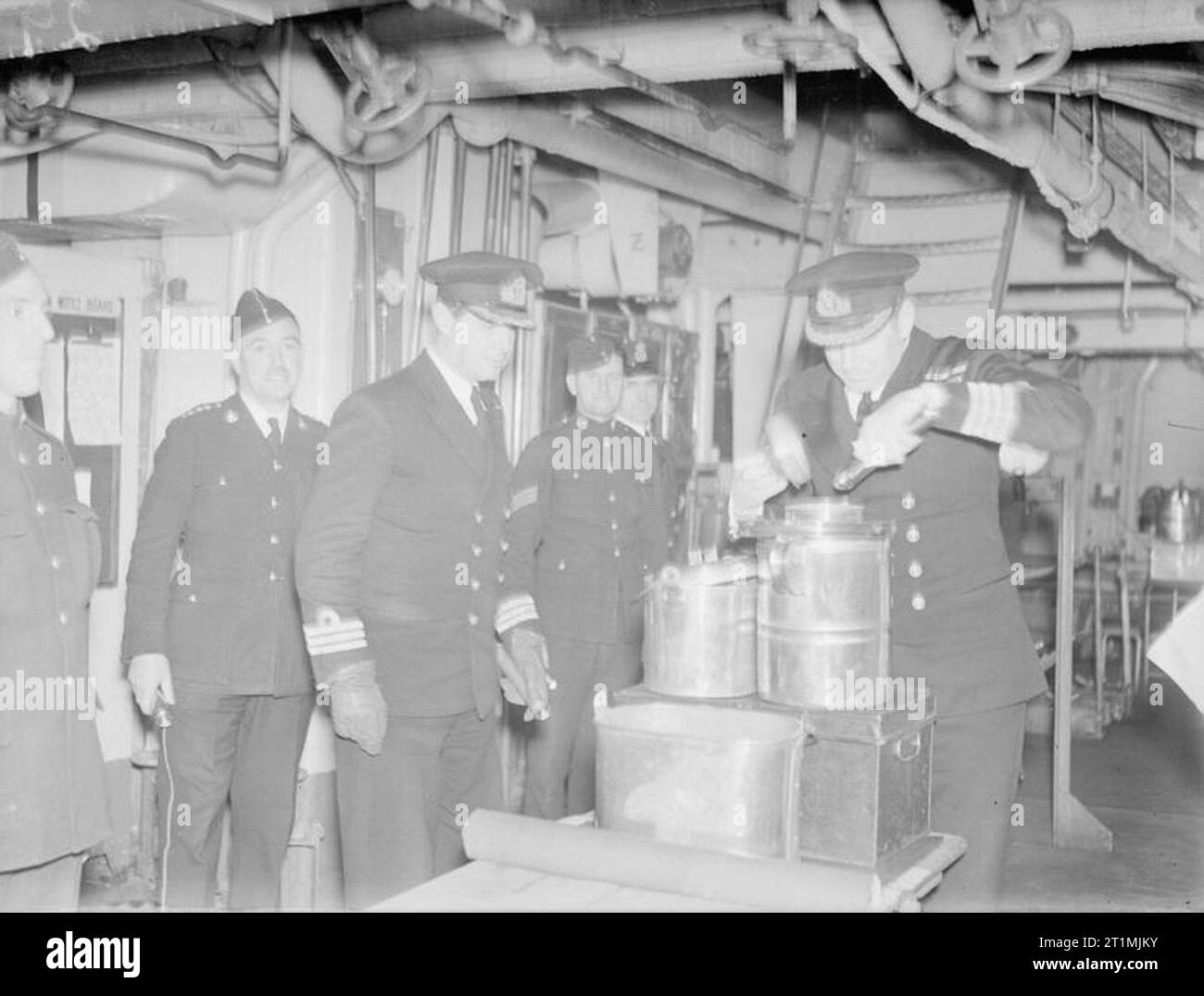 The Royal Marines. With the Royal Marines of the Home Fleet, October and November, 1942. 'Captain's rounds'. The Captain of the cruiser, HMS CUMBERLAND, inspecting mess traps on the Marines' messdeck, or 'barracks', as the Marines themselves prefer to call it. Even today the 'barracks' are generally situated between the officers' quarters and the seamens' messdecks, a quaint survival of the times when one of the chief duties of the Marines was to act as policemen and preserve discipline on board. Stock Photo