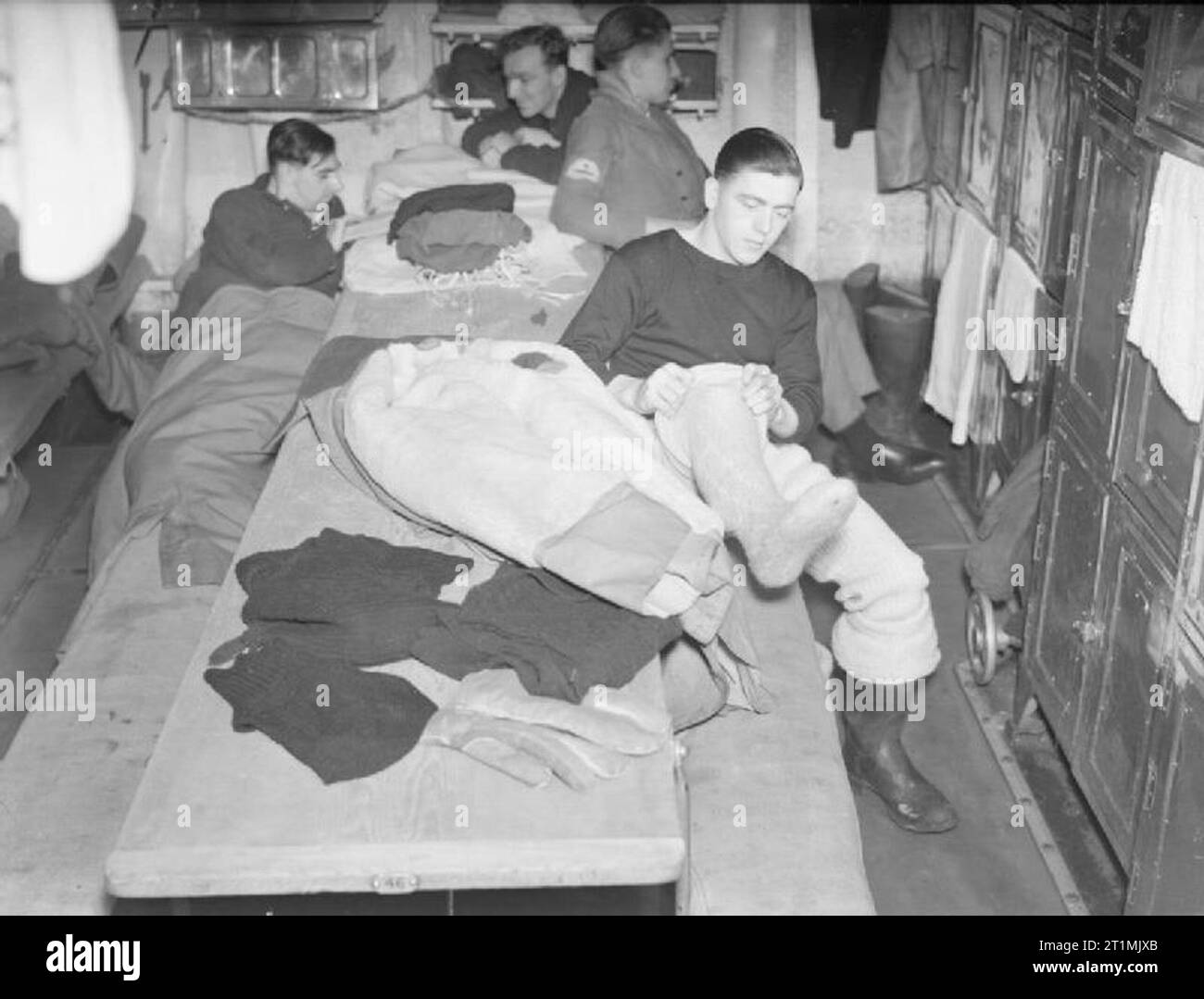 Convoy To Russia, With a British Cruiser Escort on Arctic Lifeline. December 1941, on Board the Cruiser HMS Sheffield. Taking convoys to Arctic Russia in December is a cold job and all personnel obliged to keep watches in the open are issued with arctic clothing to wear in addition to the comforts they already have. Here is a look-out preparing to go on watch. He has a sheepskin great-coat, sheepskin gloves, two balaclavas, thick woollen pants, two pairs of seaboot stockings and pullovers. Stock Photo