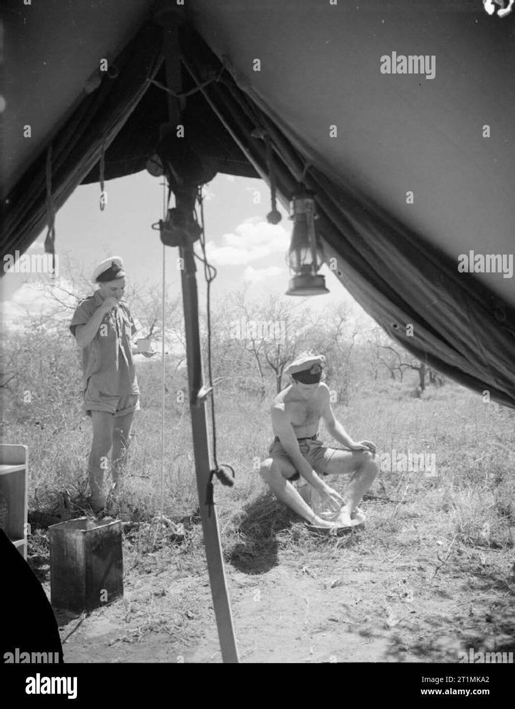 The Royal Navy during the Second World War As seen from inside their tent, two pilots of 881 Squadron, Fleet Air Arm outside their quarters at McKinnon Road, East Africa. The Royal Naval Air Station was built deep in the African bush as a base for squadrons of the Fleet Air Arm. One of the men is taking a foot bath against dust and flies. Stock Photo