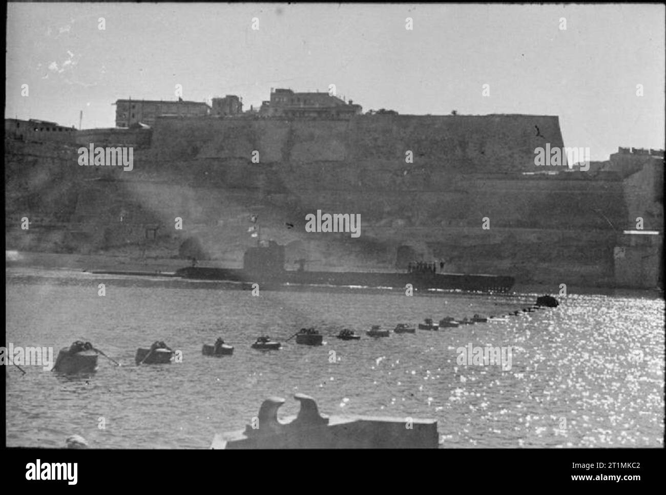 The Royal Navy during the Second World War HMS UNRUFFLED returning to harbour in Malta after a patrol in the Mediterranean where she supported the Allied victories in North Africa, Sicily and Italy. Here the submarine is just making its way past the boom. The ancient walls of the harbour are towering down on UNRUFFLED. Stock Photo