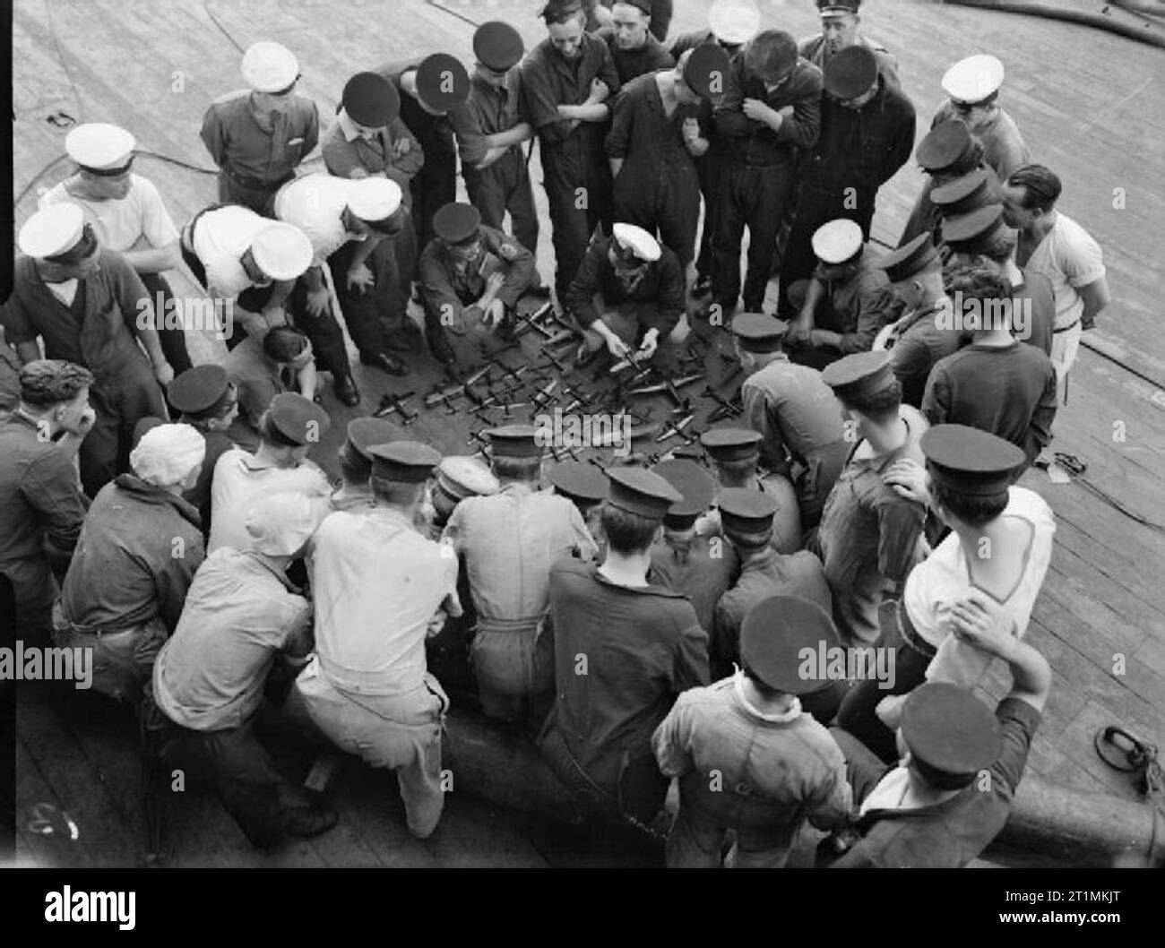 The Royal Navy during the Second World War An aircraft recognition class learning from models on the focsle of HMS RODNEY. The group are stood round a selection of model aircraft on the deck of the battleship. Stock Photo