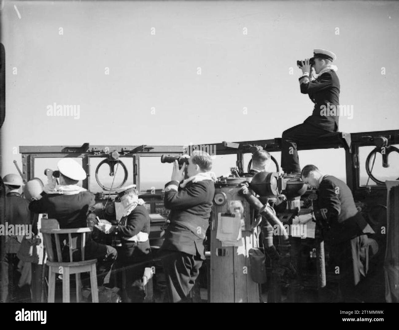 The Royal Navy during the Second World War The Commanding Officer of HMS ORION, Captain J P Gornall, of Steyning, Sussex, perched on the baffle of the cruiser's bridge, to observe the effect of the bombardment in support of Fifth Army's landings at Anzio in the opening stages in the battle for Rome. As well as assisting with coastal bombardments the cruiser helped escort the landing craft of all types that swept into the beach in the wake of the minesweepers. Stock Photo