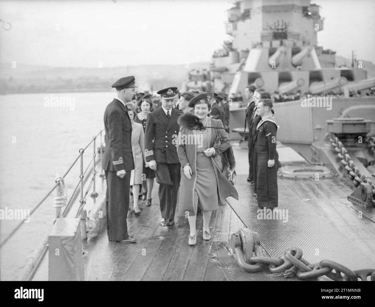 The Royal Navy during the Second World War HM Queen Elizabeth walking along the focsle of HMS KING GEORGE V at Greenock followed by Princess Margaret and Princess Elizabeth during a farewell visit before the battleship left to join Britain's East Indies Fleet. The twin and quadruple 14 inch gun turrets can be seen in the background. Stock Photo