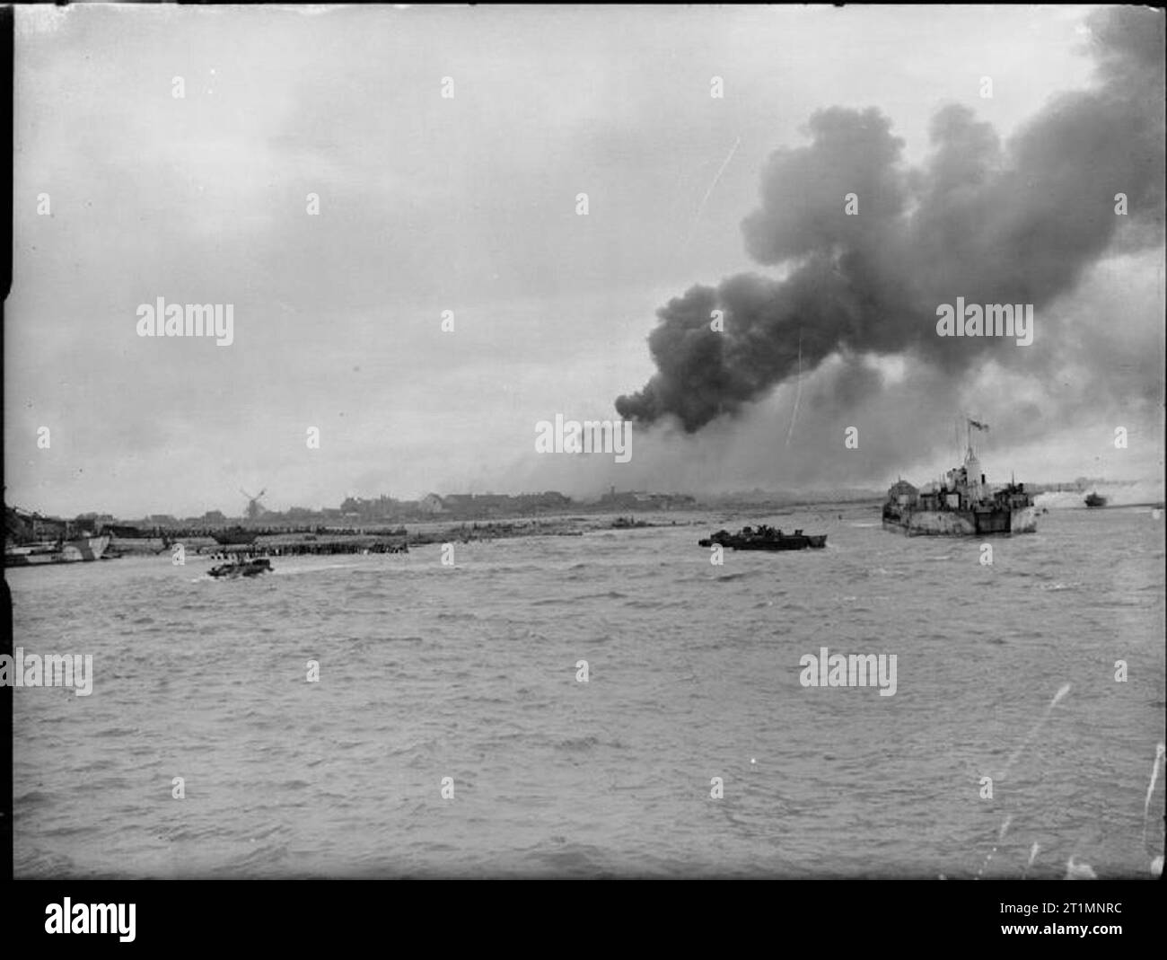 The Royal Navy during the Second World War DUKWs or 'Ducks' head towards the shore from a landing craft tank (LCT 952) whilst an Alligator personnel carrier can be seen on the beach. A large plume of smoke is rising high into the air from an enemy strongpoint on fire in the background during the landing by Royal Marine commandos on the island of Walcheren at Westkapelle, the most western point of the island, the final phase of the battle to free the Belgian port of Antwerp. Stock Photo