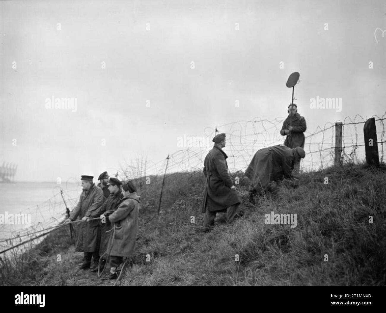 The Royal Navy during the Second World War Royal Engineers clearing the banks discover a land mine by listening apparatus, and a sergeant digs it out while the searching party waits to move on. Stock Photo