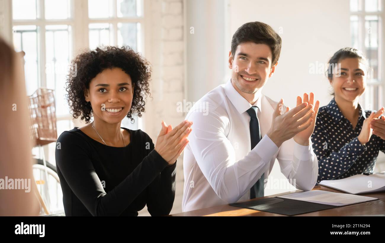 Happy motivated young diverse business team applauding speaker after presentation Stock Photo