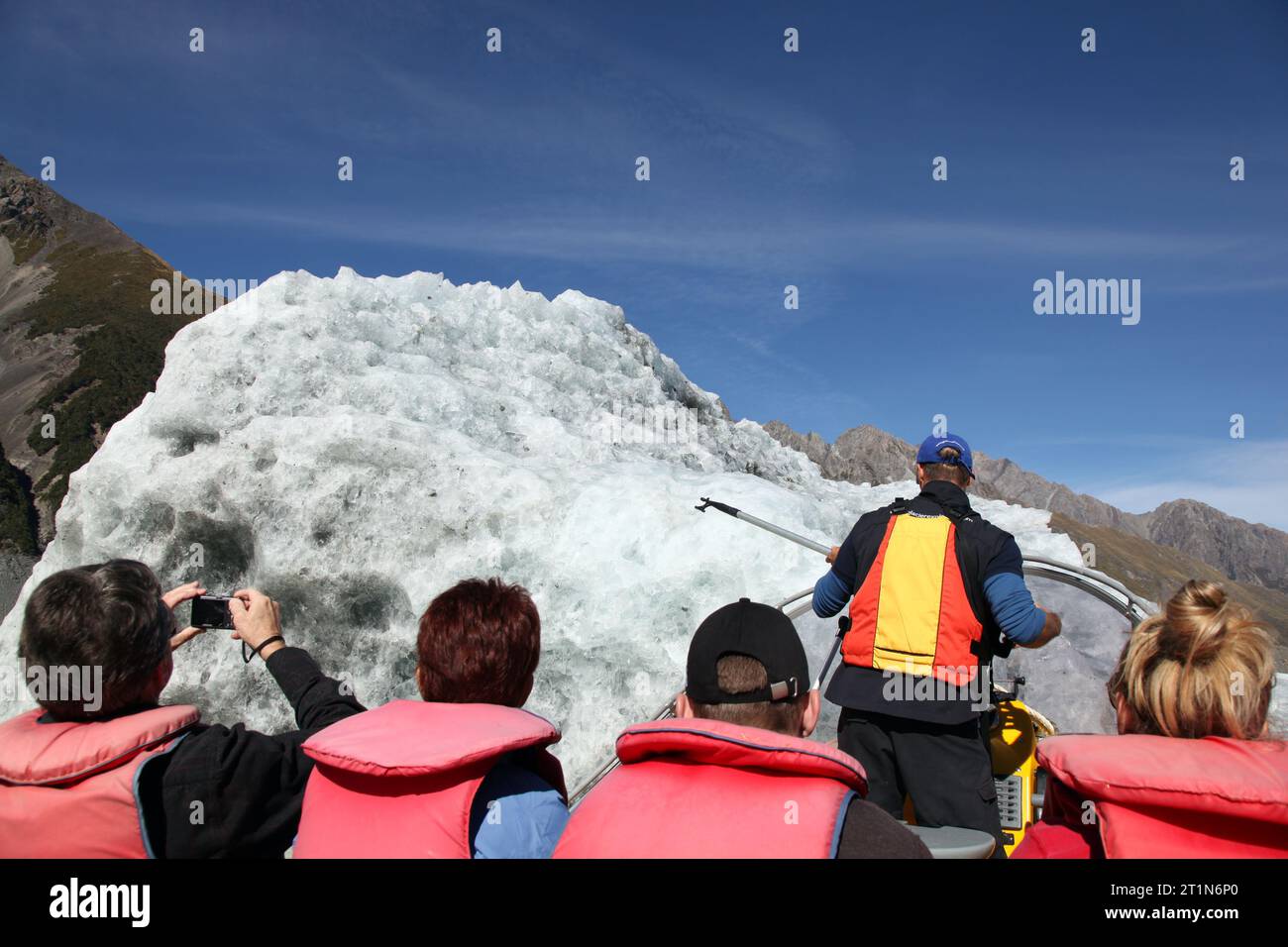 TASMAN LAKE - APRIL 12: A group of tourist watch as the tour guide brings the boat to an iceberg on Tasman Lake on April 12, 2011 in Tasman Lake, New Stock Photo
