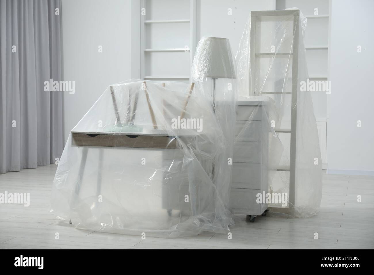 Modern furniture covered with plastic film at home Stock Photo