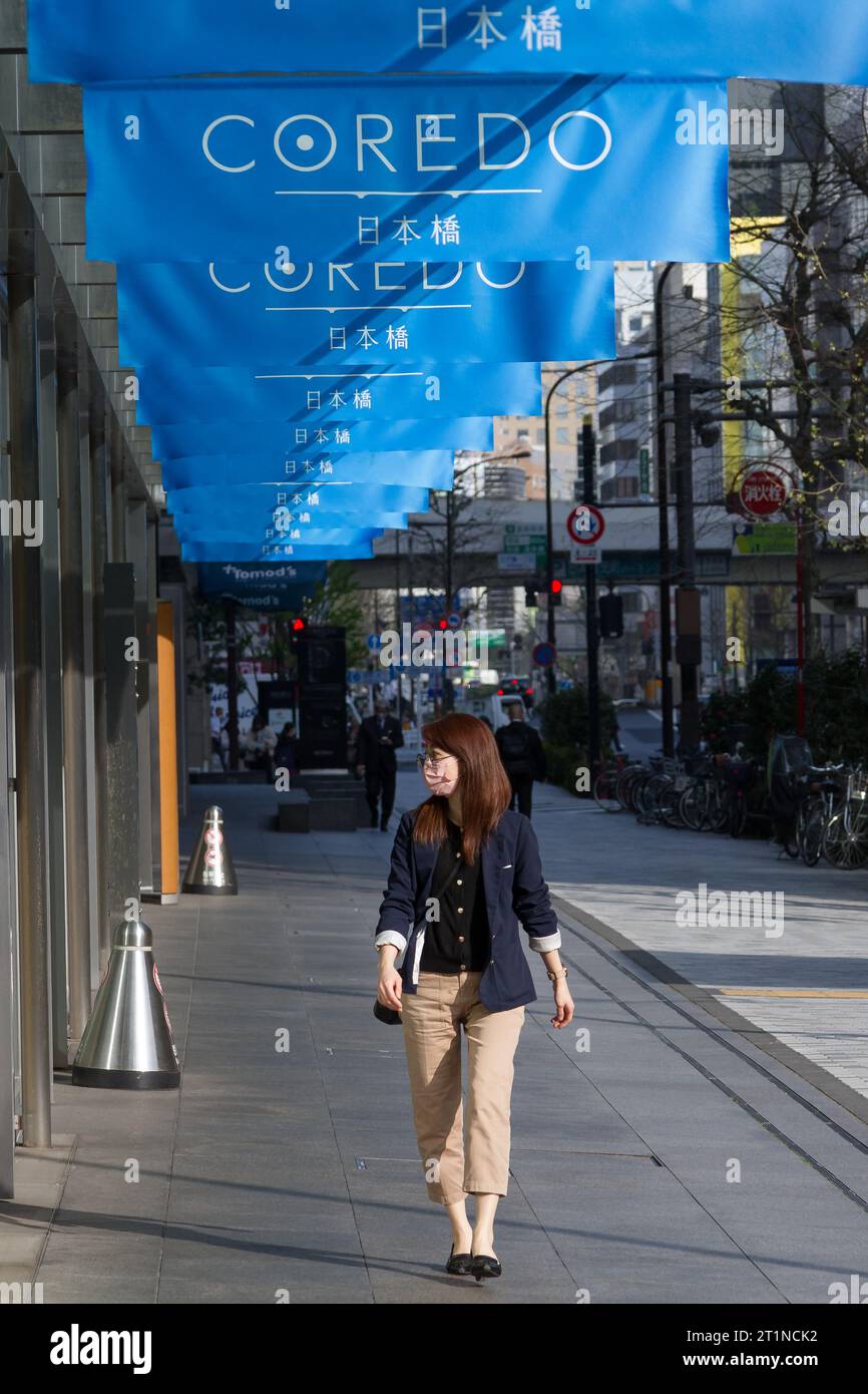 A Japanese woman walks under banners for the Coredo Shopping complex in Nihonbashi, Tokyo, Japan. Stock Photo