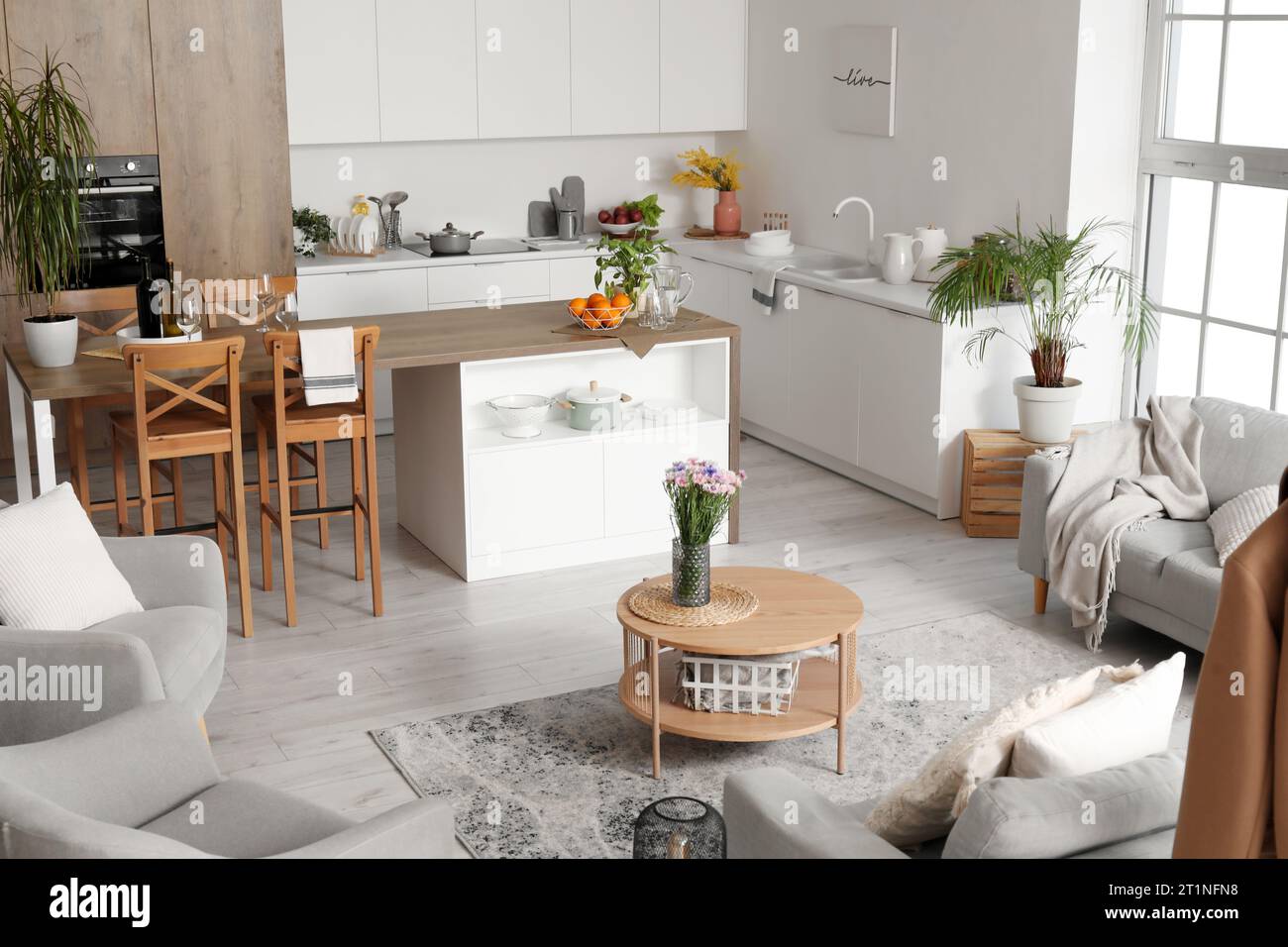 Interior of light open plan kitchen with coffee table and grey sofa ...