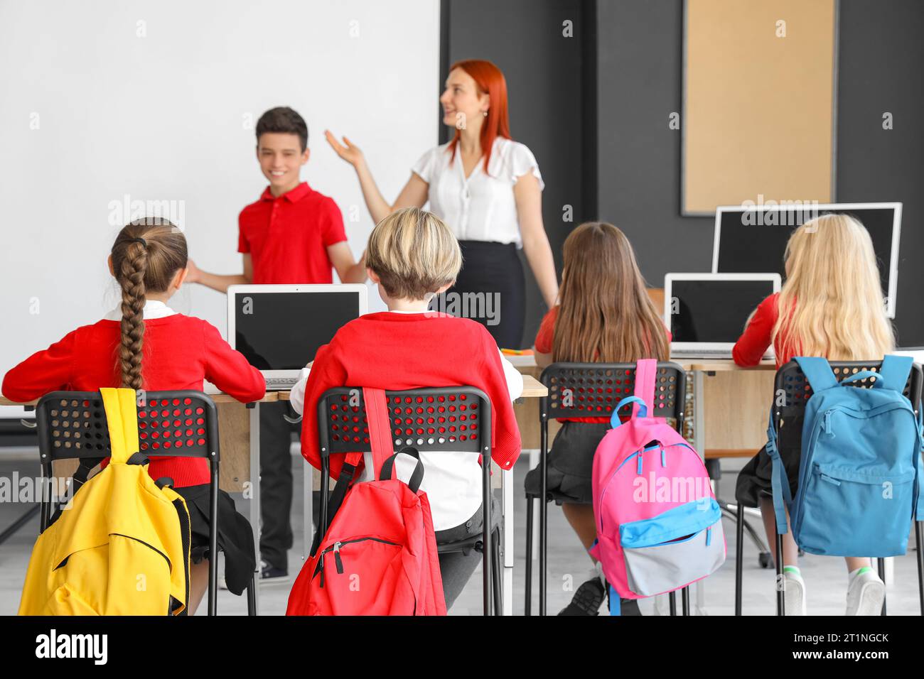 Little children with teacher studying at school computer lab, back view ...