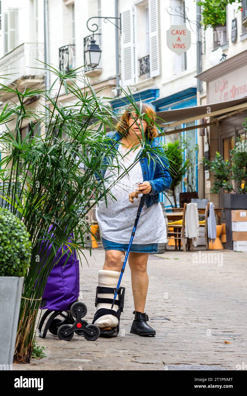 Woman in street wearing post surgery medical supportive boot and plaster cast - Loches, Indre-et-Loire (37), France. Stock Photo